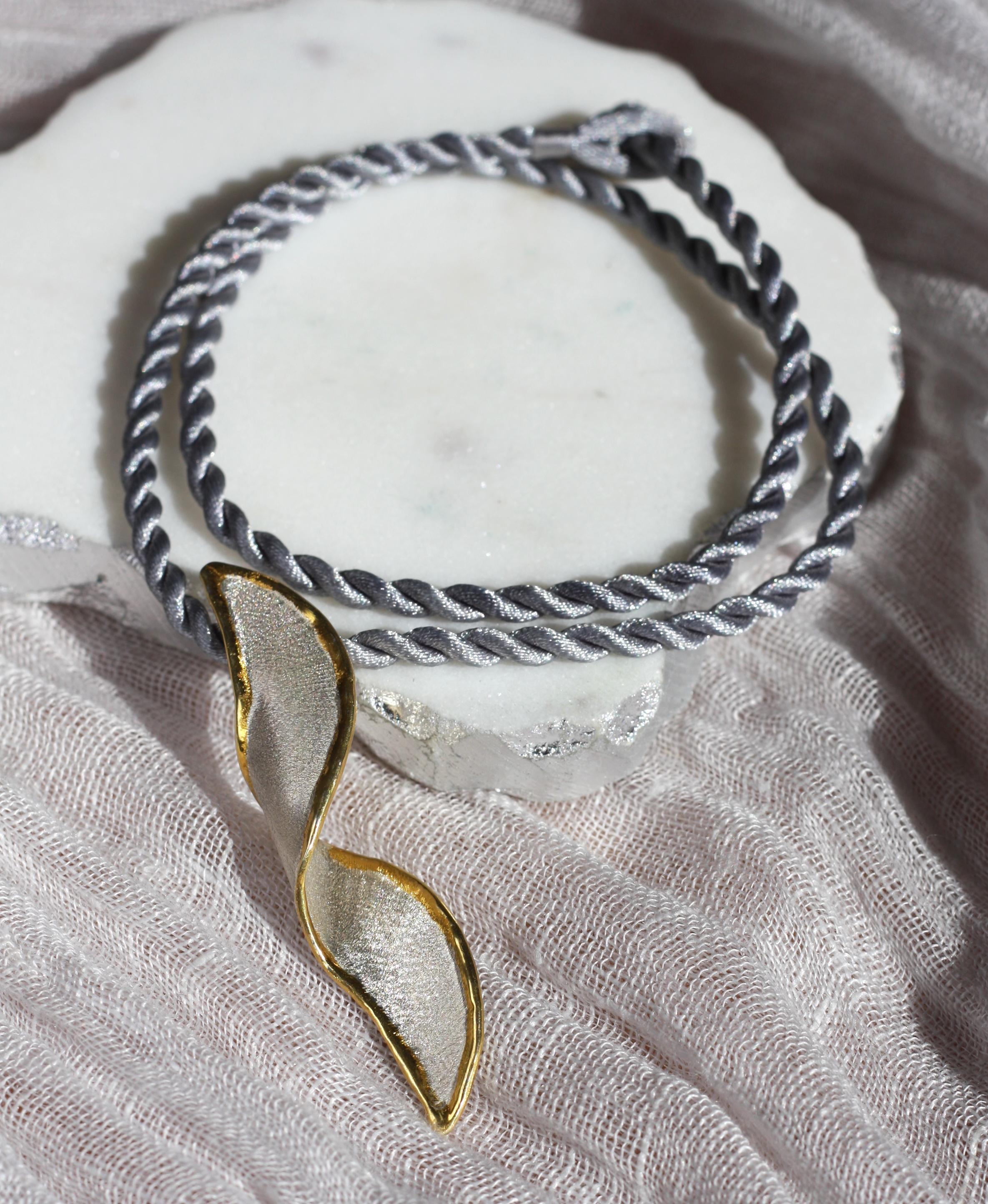 Ti presentiamo il pendente di Yianni Creations a forma di spirale della collezione Midas, realizzato a mano in argento 950 e placcato in palladio per resistere agli agenti atmosferici. Questo accattivante ciondolo artigianale nella sua purezza