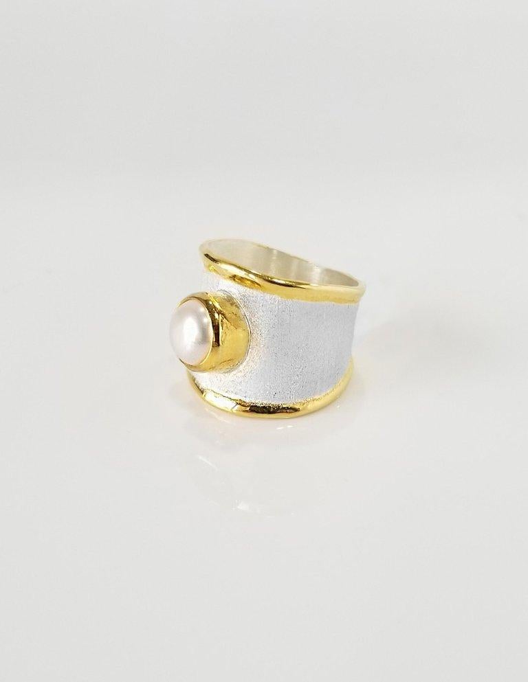 L'anello a fascia di Yianni Creations è realizzato a mano in argento pregiato con una scorta di oro giallo a 24 carati e presenta una perla d'acqua dolce di 7,0 mm, completata da una tecnica di lavorazione unica: una texture spazzolata e bordi