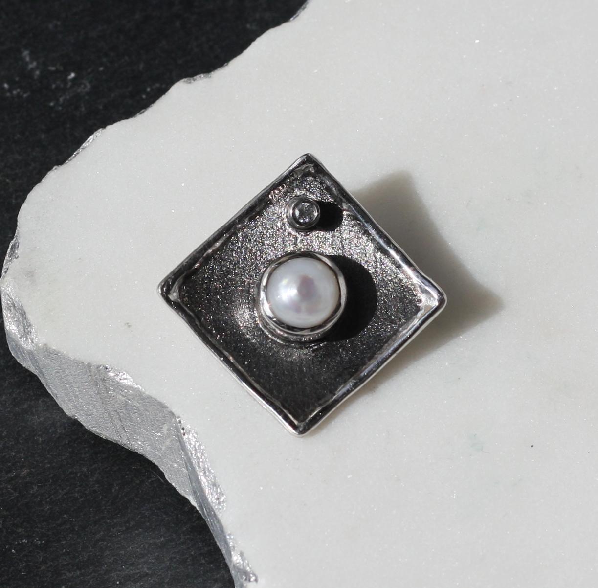 This is a geometrically shaped pendant enhancer from Yianni Creations all done by hand from fine silver 950 purity and plated with palladium to resist tarnish. This slide from Hephestos Collection is finished with black rhodium. Against the black