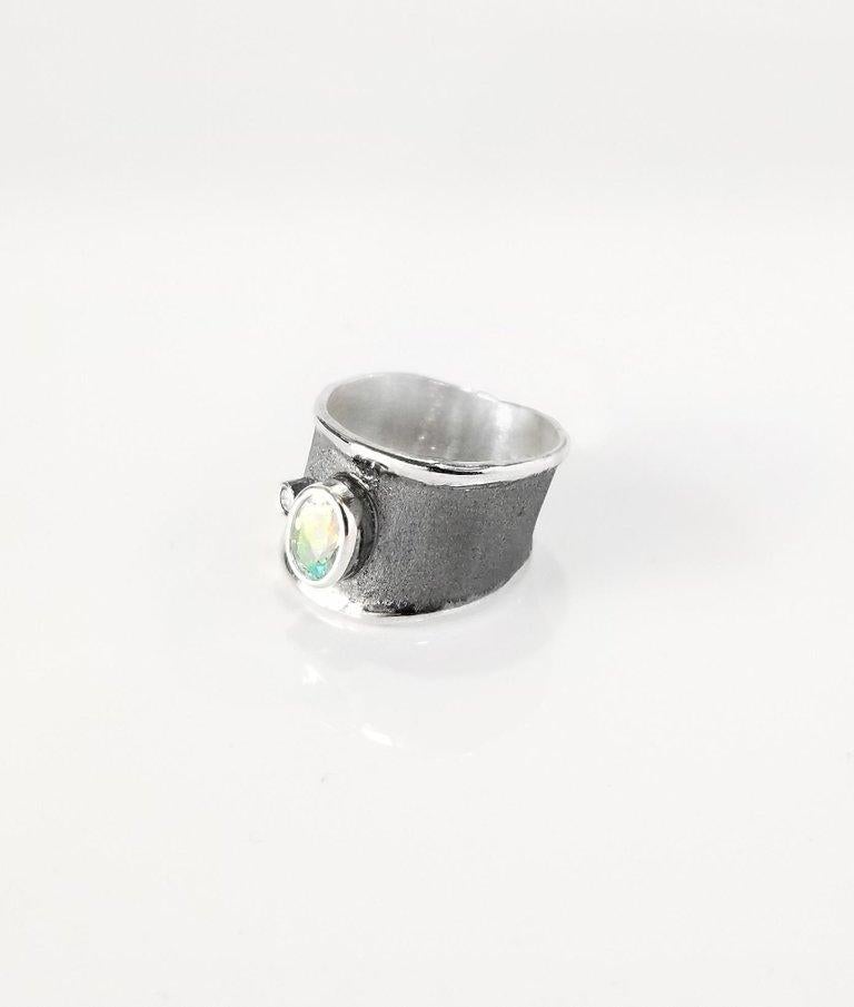 This Yianni Creations handcrafted fine silver (950 purity) wide band ring is plated with palladium to resist elements. This gorgeous band features a 0.75 Carat Natural Aquamarine and a 0.03 Carat Brilliant cut Diamond contrasting on a unique velvet