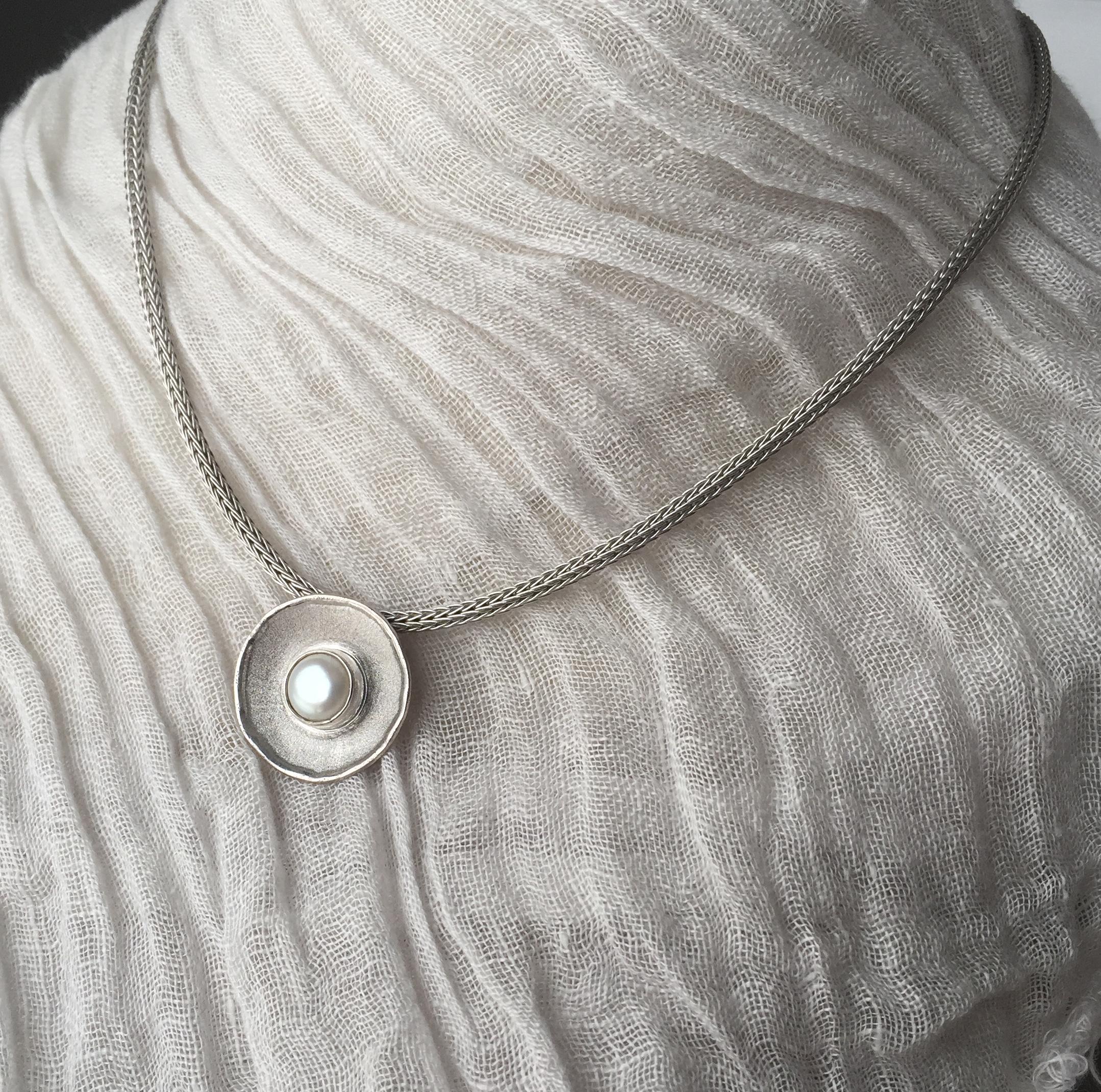 From Yianni Creations Ammos Collection, this is a handmade artisan slide from fine silver 950 purity and plated with palladium to resist against elements. This pendant enhancer features an 8mm round freshwater pearl. This round pendant combines two