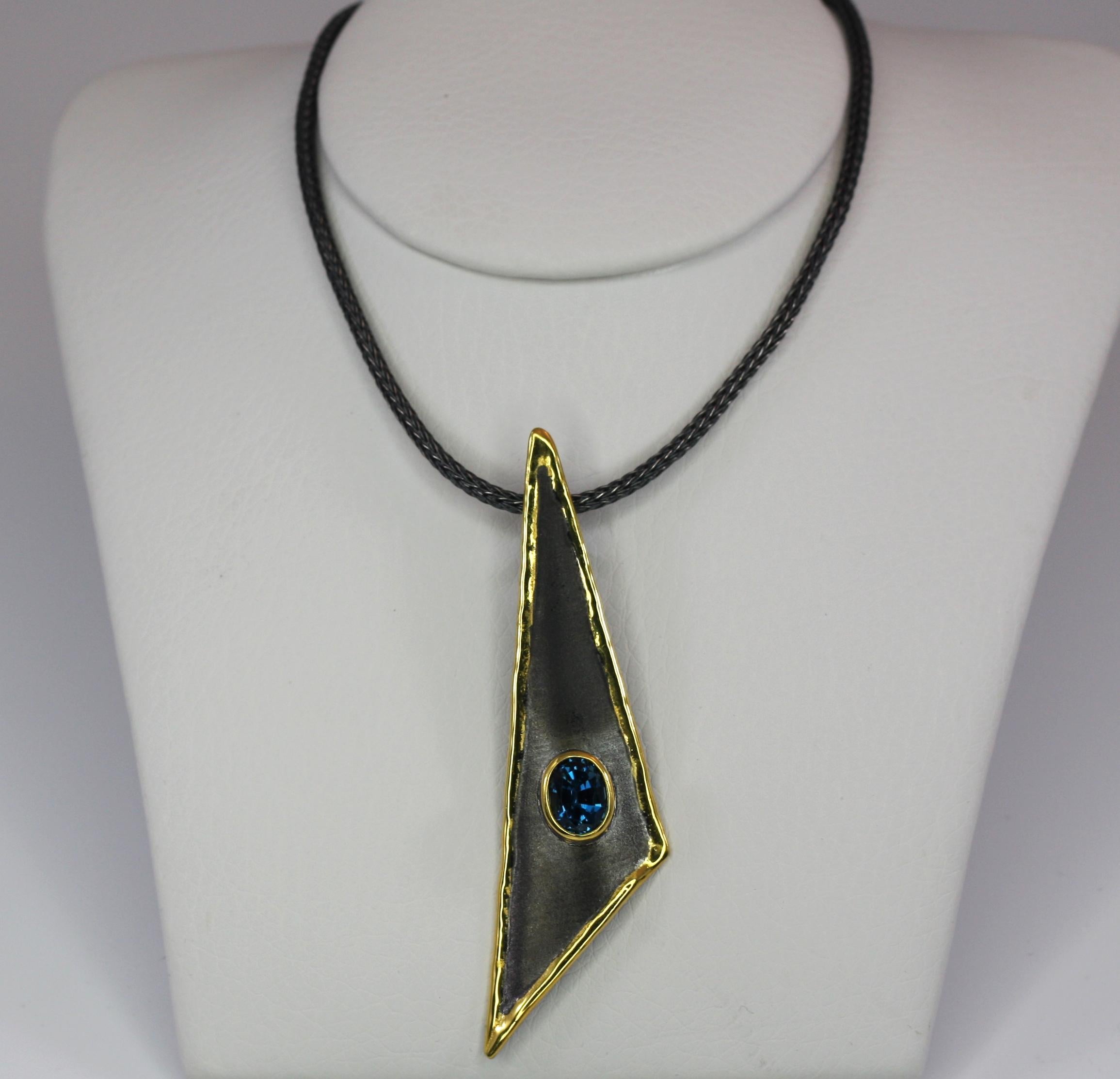 Presenting Yianni Creations Fine Silver pendant necklace all handcrafted in Greece from a silver 950 purity and plated with Black Rhodium and pure gold on the edges. The pendant decorates a 1.60 Carat oval cut London Blue Topaz. The unique look is