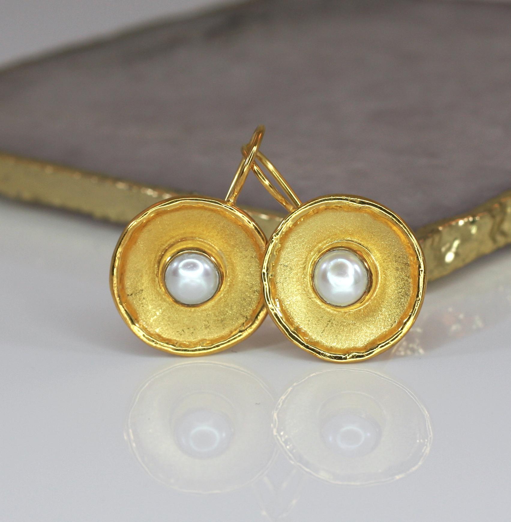 These are Yianni Creations handmade artisan earrings crafted in Greece from 18 Karat Yellow Gold. These round dangle earrings feature 7MM freshwater pearl. The unique look is created by combining two ancient techniques - brushed texture and