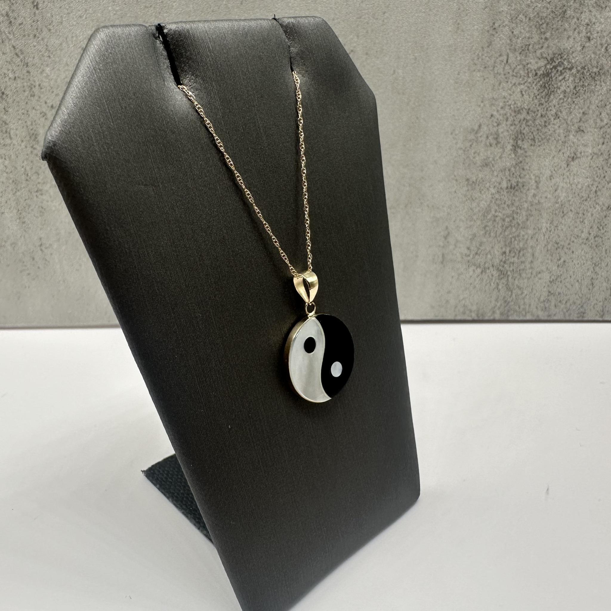 Cet élégant collier Yin et Yang en or jaune 14kt présente un étonnant motif en onyx et en nacre, symbolisant l'équilibre et l'harmonie. Avec un diamètre de 14,5 mm, il offre un aspect saisissant, et la longueur de 18 pouces permet un ajustement