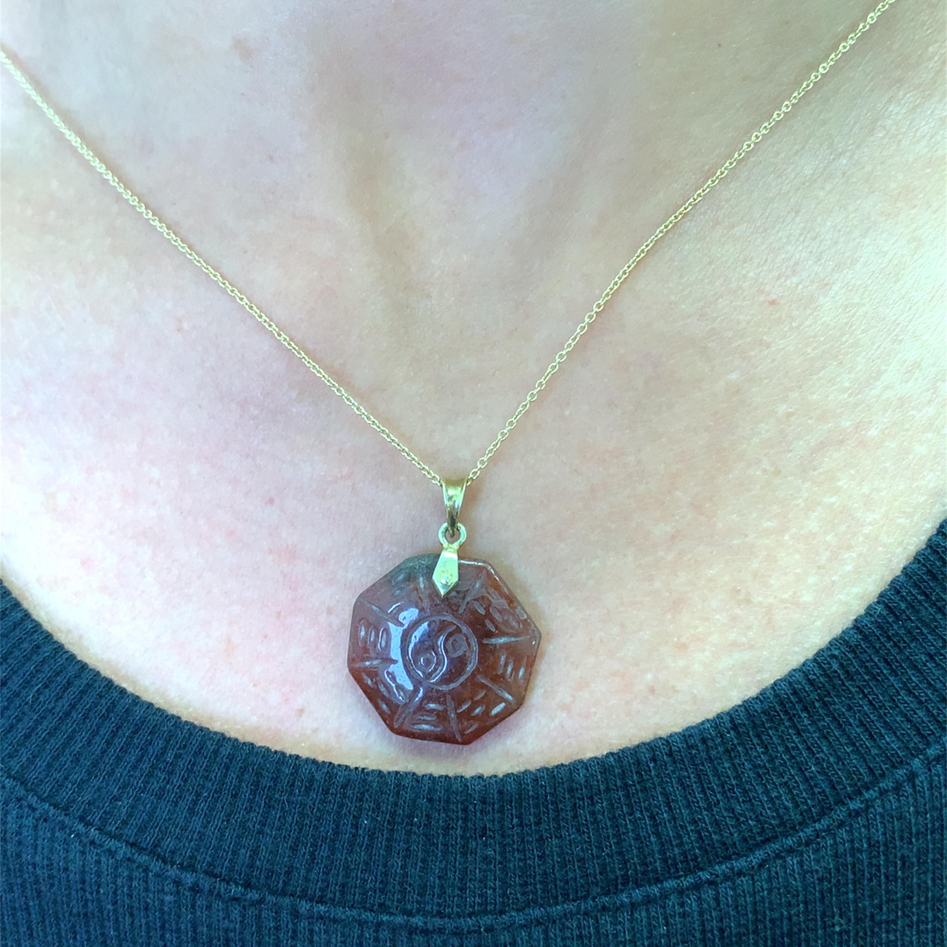 Elevate your style with this distinctive yellow gold pendant. Featuring a meticulously carved octagon shaped carnelian  lm, this pendant showcases a rich brown hue. Its unique design and translucent quality make it a captivating piece, perfect for