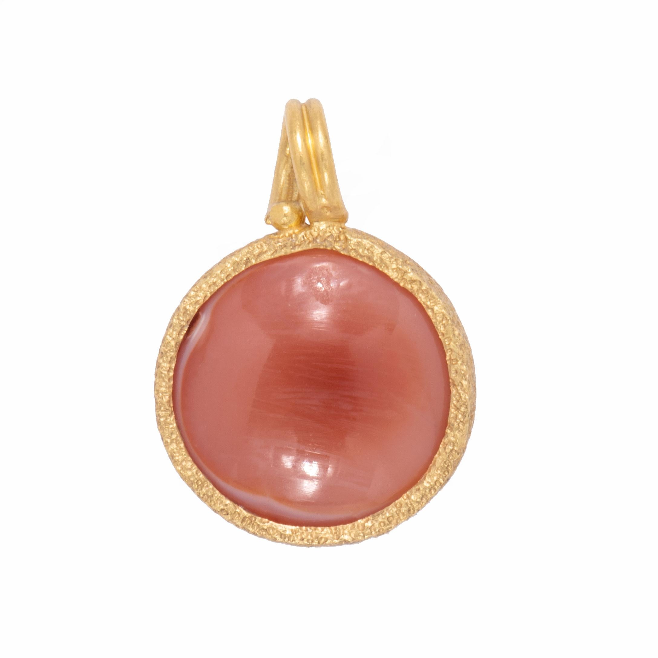 A natural orange curved disk of agate is set in 22 karat gold with a twist bail. The Yin/Yang symbol from ancient Chinese philosophy displays the principle that contradictory opposites such as light and dark, male and female cannot exist without the