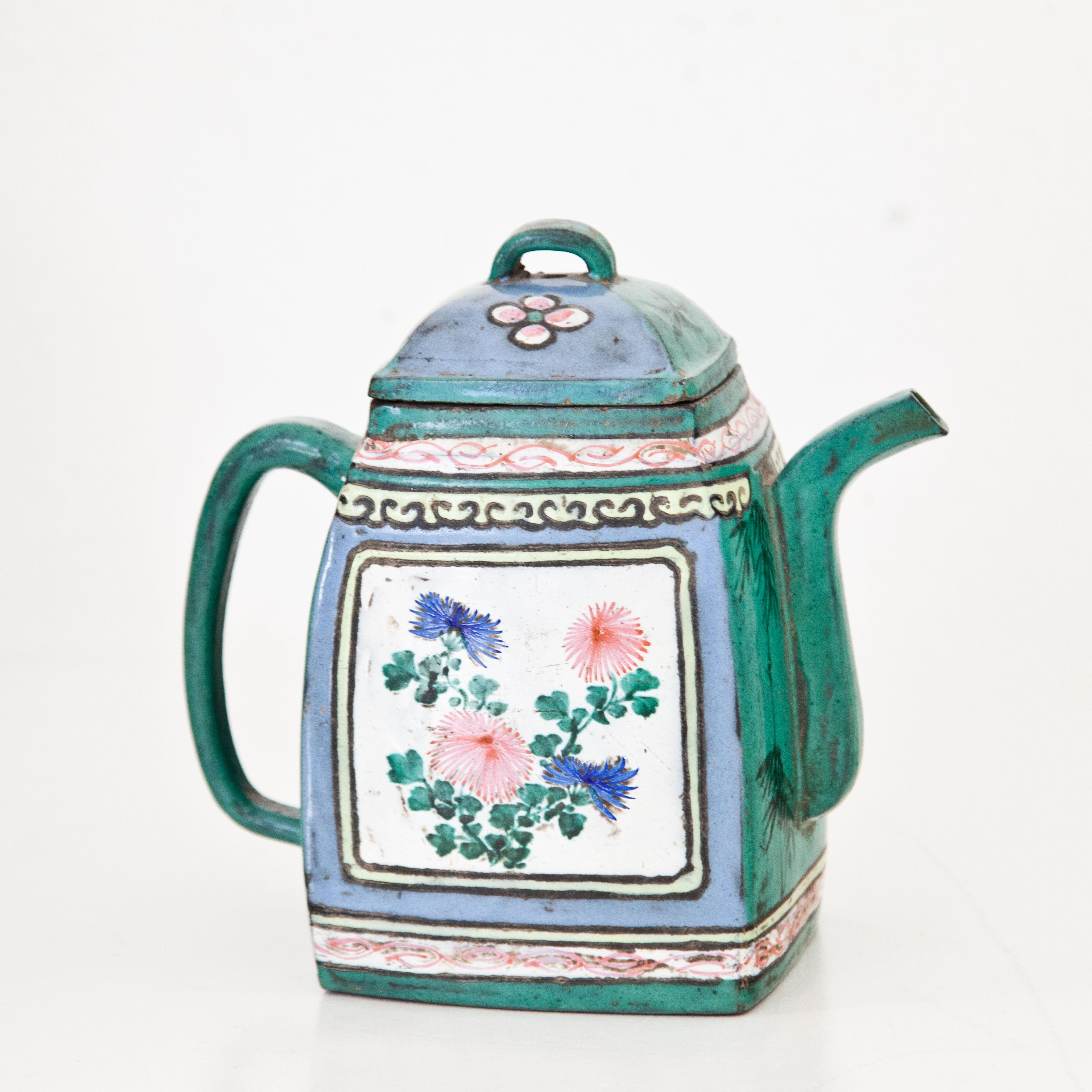 Small teapot with square basic shape and green-blue fond on brown clay. The sides with polychrome floral and bird motifs. Small crack in the lid. Maker‘s mark Xu Fei Long stamped on the bottom.