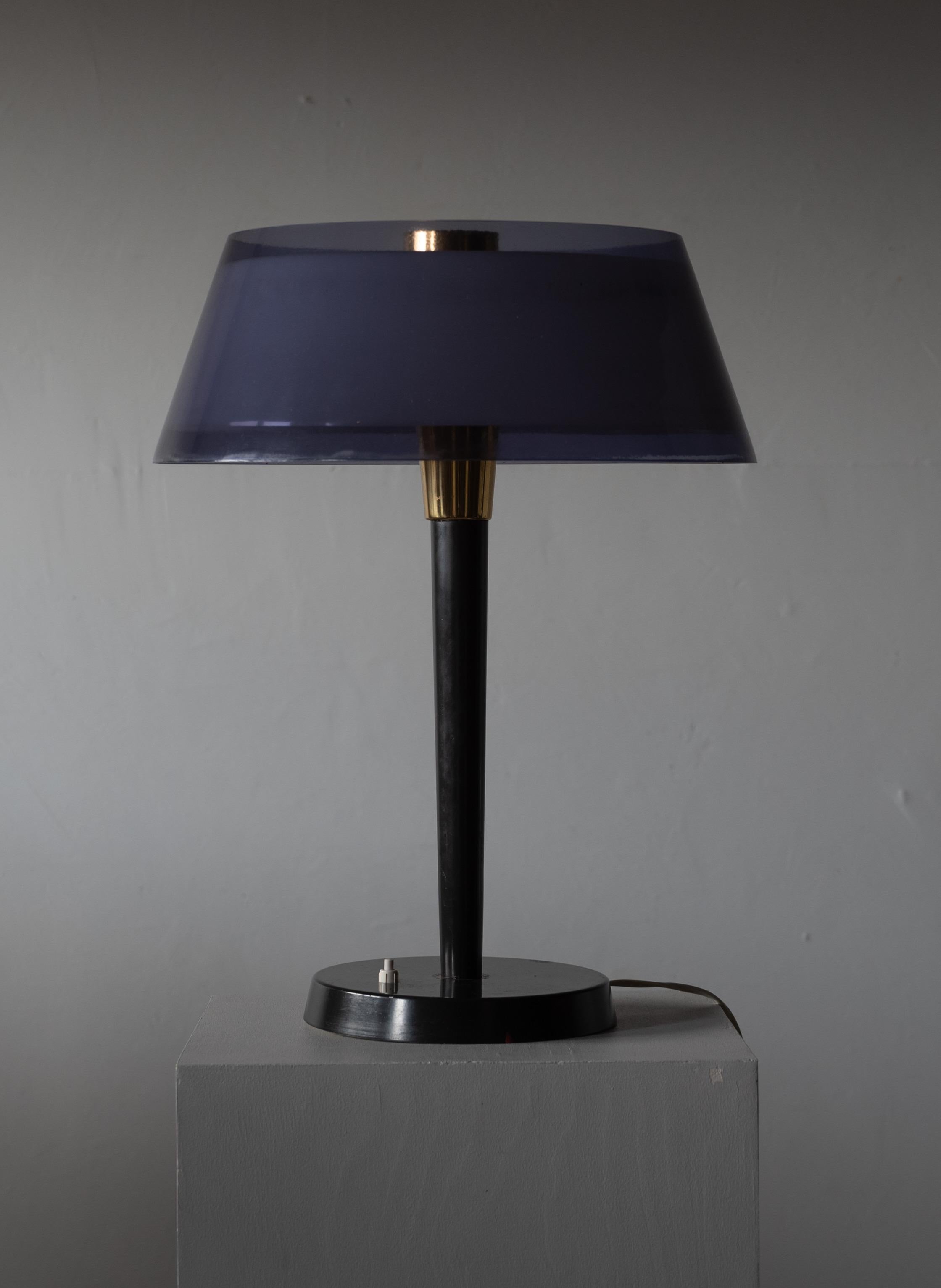 A table lamp, designed by Yki Nummi (Finnish, 1925-1984). Produced by Orno, 1960s.

In brass, black-lacquered metal. Light is diffused by one white acrylic shade and one purple acrylic lampshade layered on each other.
 