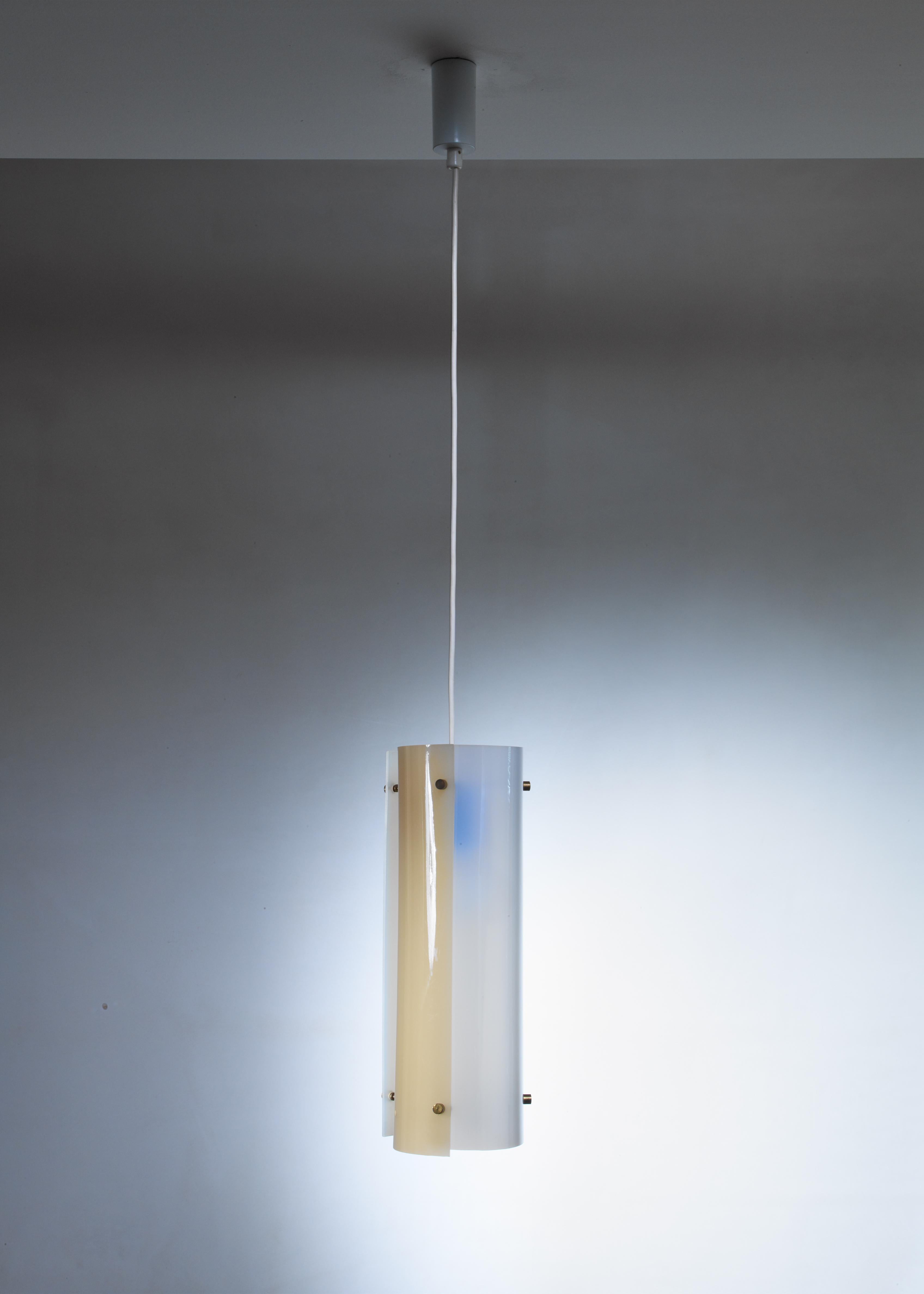 A Yki Nummi model 64-430 pendant lamp for Orno, made of three curved white and soft yellow plexiglass elements, held together by thin brass rods. The colored plexiglass creates a beautiful, atmospheric light distribution.