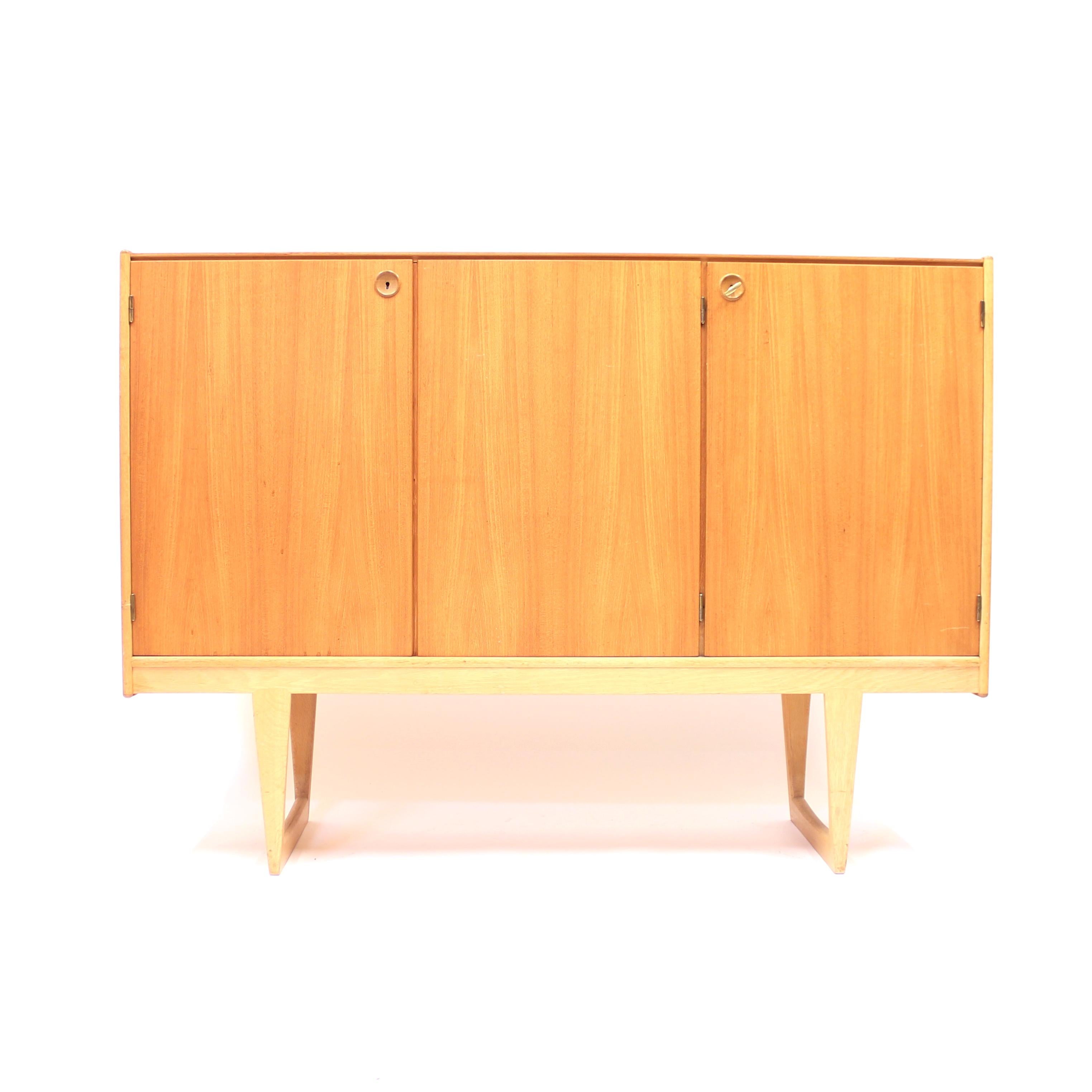 Sideboard, model Tokyo, made from teak and oak designed by Yngvar Sandström for NK (Nordiska Kompaniet) in 1959. This is the largest and tallest, quite rare, example in the series with three front doors hiding shelves and three drawers to the right.