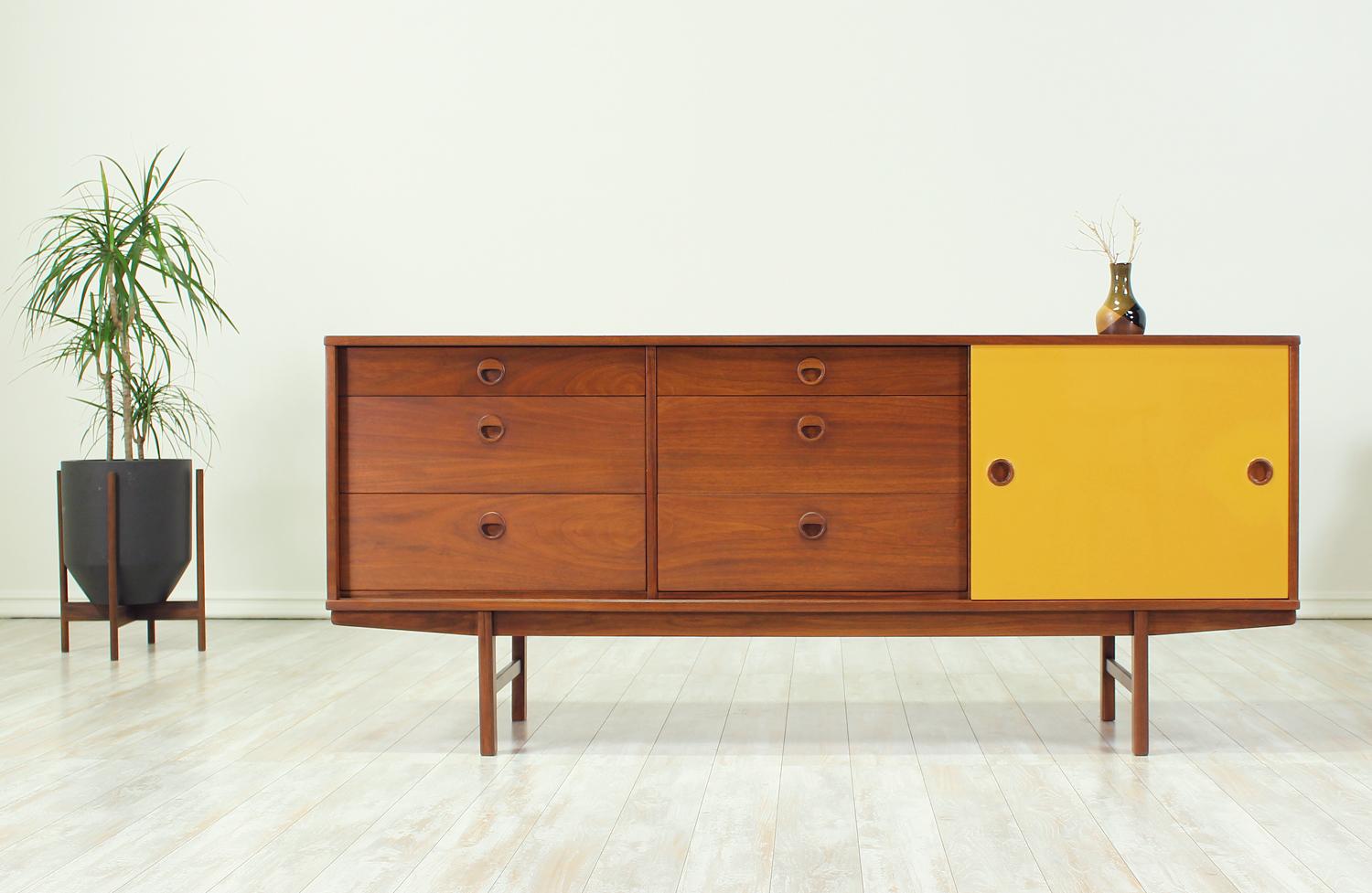 Scandinavian Modern credenza designed by Yngve Ekstrom for Dux of Sweden circa 1950s. The model 504 has been crafted in walnut wood and features six dovetailed drawers on the left side and a shelved compartment hidden behind a sliding mustard-yellow