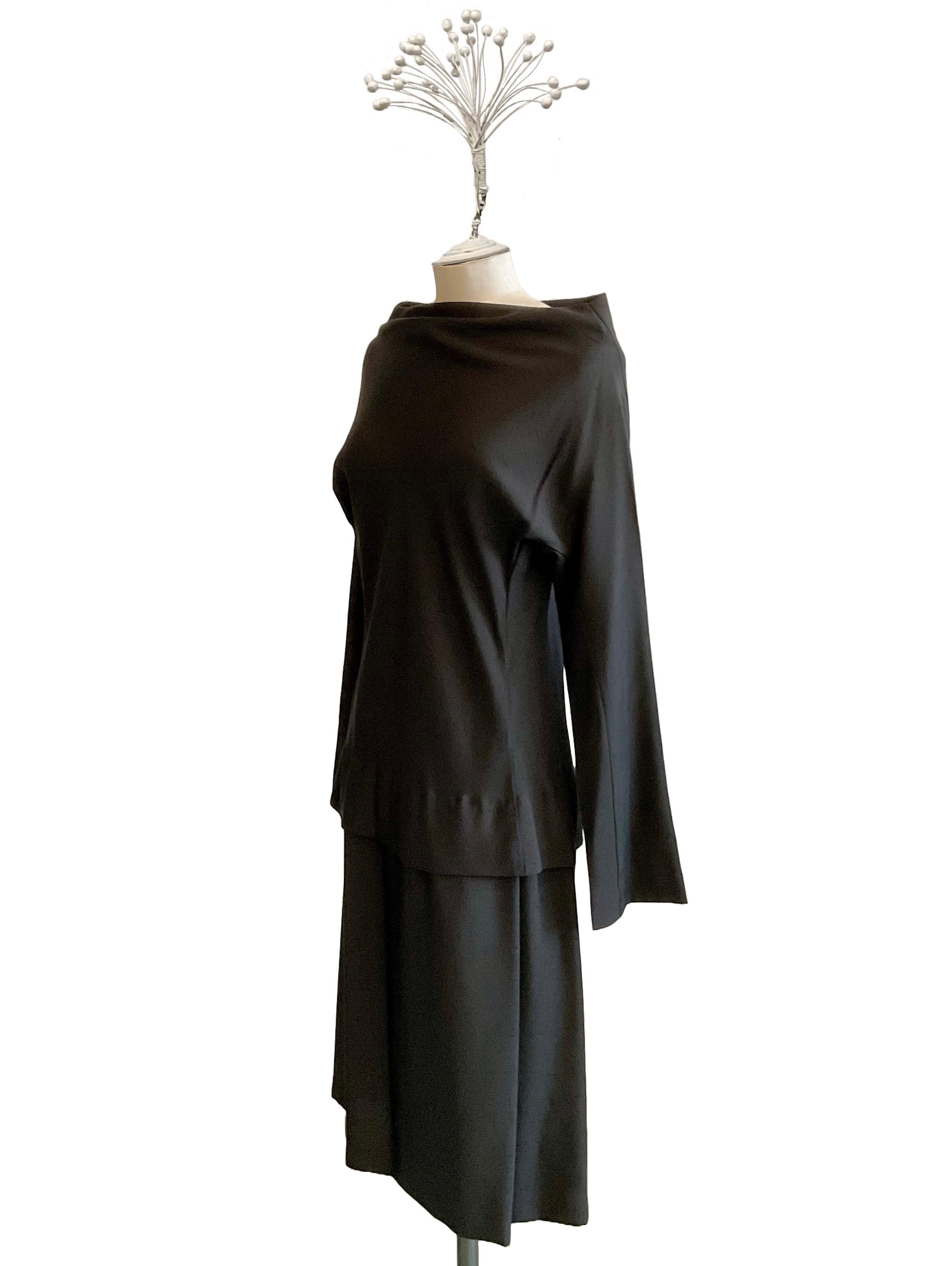Abito nero con manica lunga a kimono di Yohji Yamamoto dei primi
anni 2000.
L'abito, lunghezza midi, ha lo scollo a cratere ed una baschina
posizionata poco sotto alla vita.
Sul davanti, a sinistra, dalla baschina parte una piega profonda