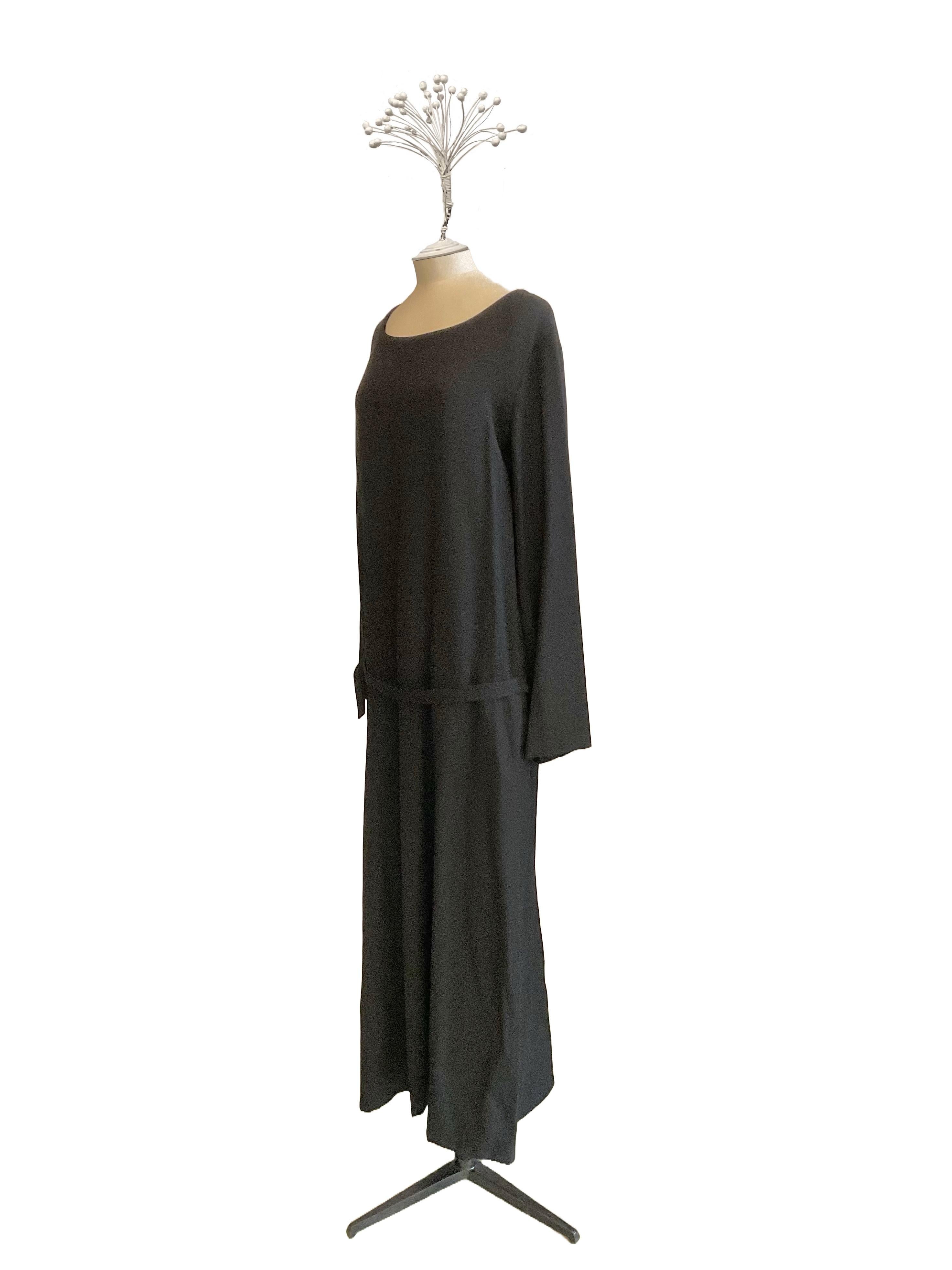 Abito tunica Nero con manica lunga di Yohji Yamamoto dei primi anni 2000. L'abito è lungo, ha la linea morbida e lo scollo ovale. Possède une piccola cintura dello stesso tessuto con fibbia Regolabile.
La cintura è libera è fissata solo sui fianchi.