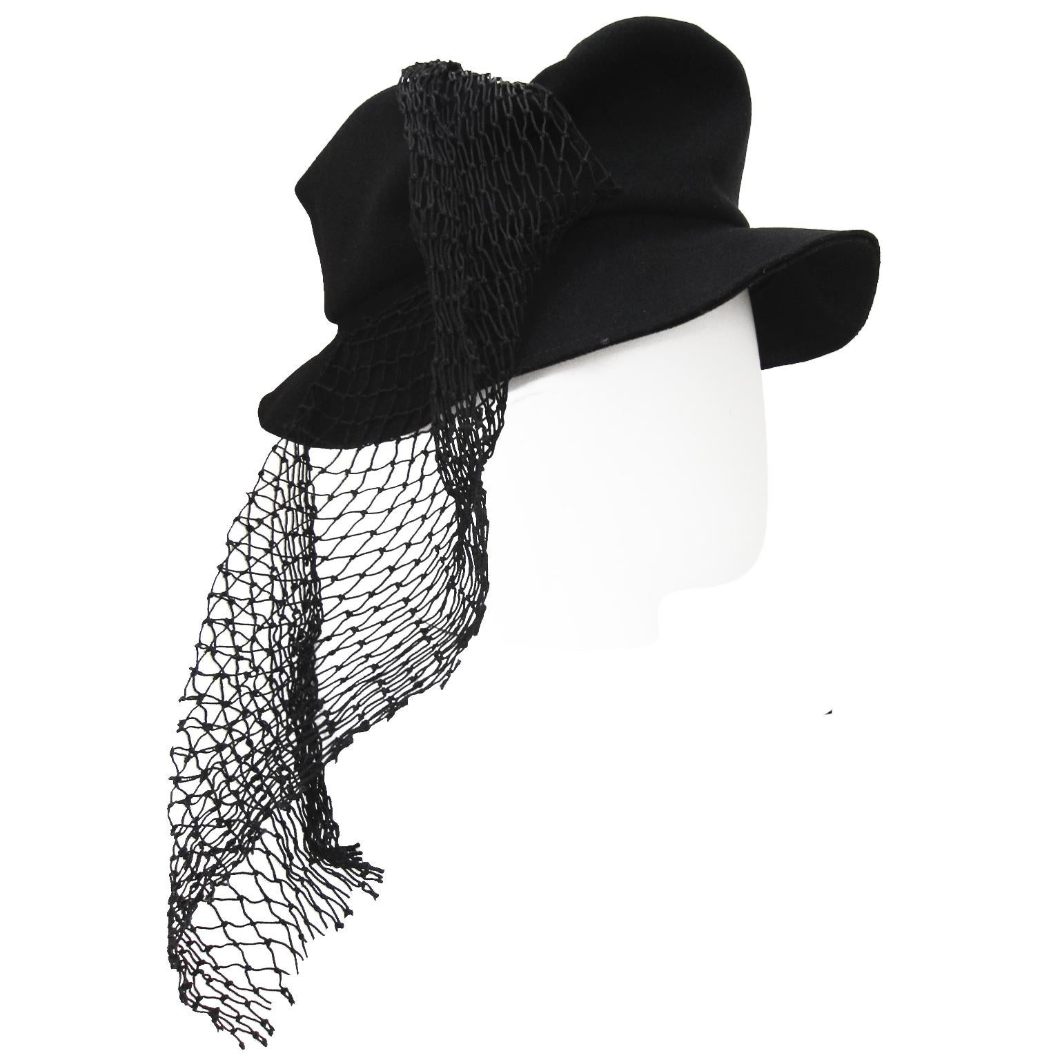 Yohji Yamamoto black hat from AW 1995. This incredible piece was worn by Stella Tennant in the collection look book, photographer David Sims. 
The hat is in black thin wool with a flat top, asymmetric draped mesh net material. Truly amazing piece.