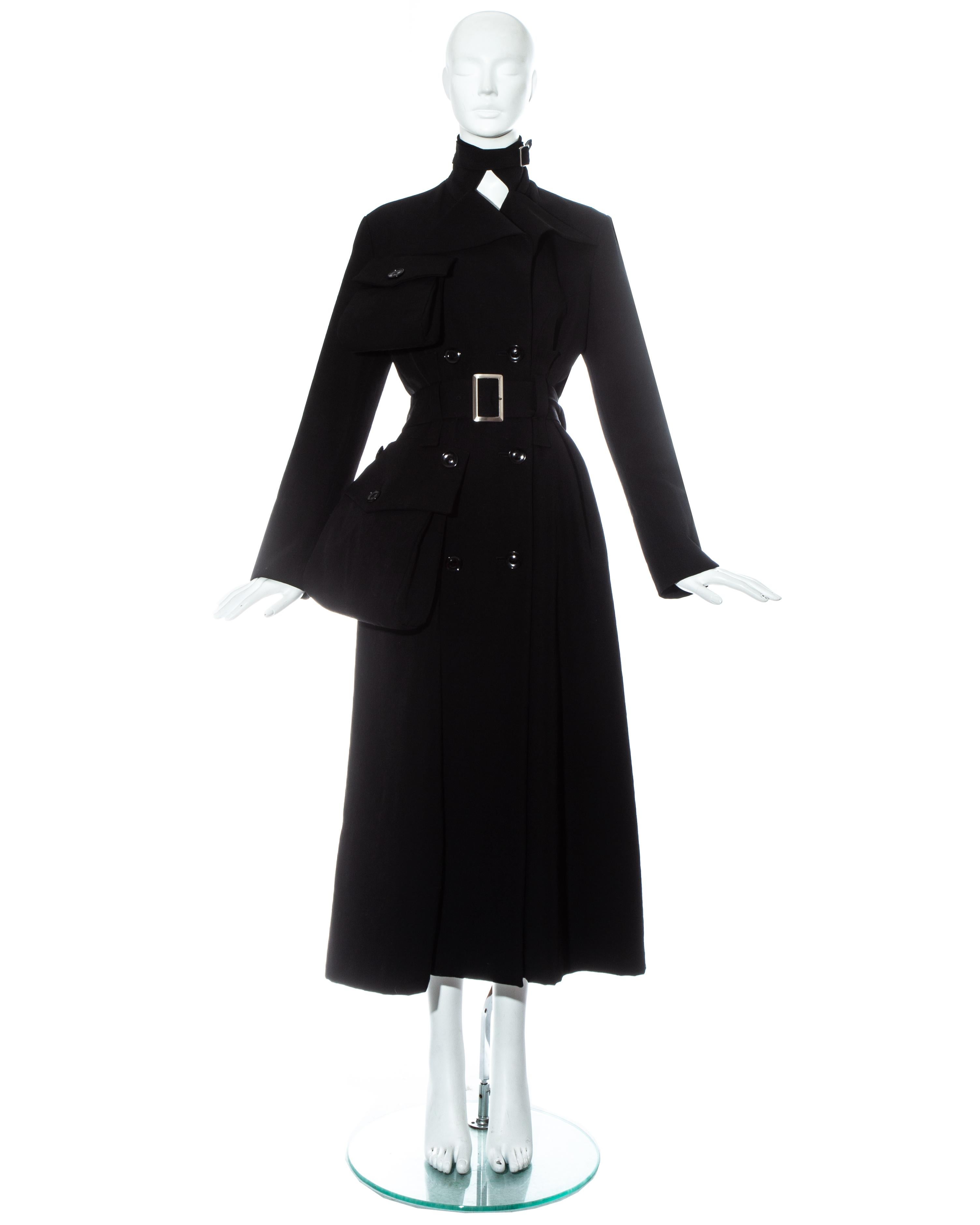 Yohji Yamamoto; black wool gabardine maxi coat with exaggerated external flap pockets and belt buckle fastenings on waist and neck. 

Fall-Winter 2004 

- The same coat is in the permanent collection of the Victoria & Albert museum archives. 
