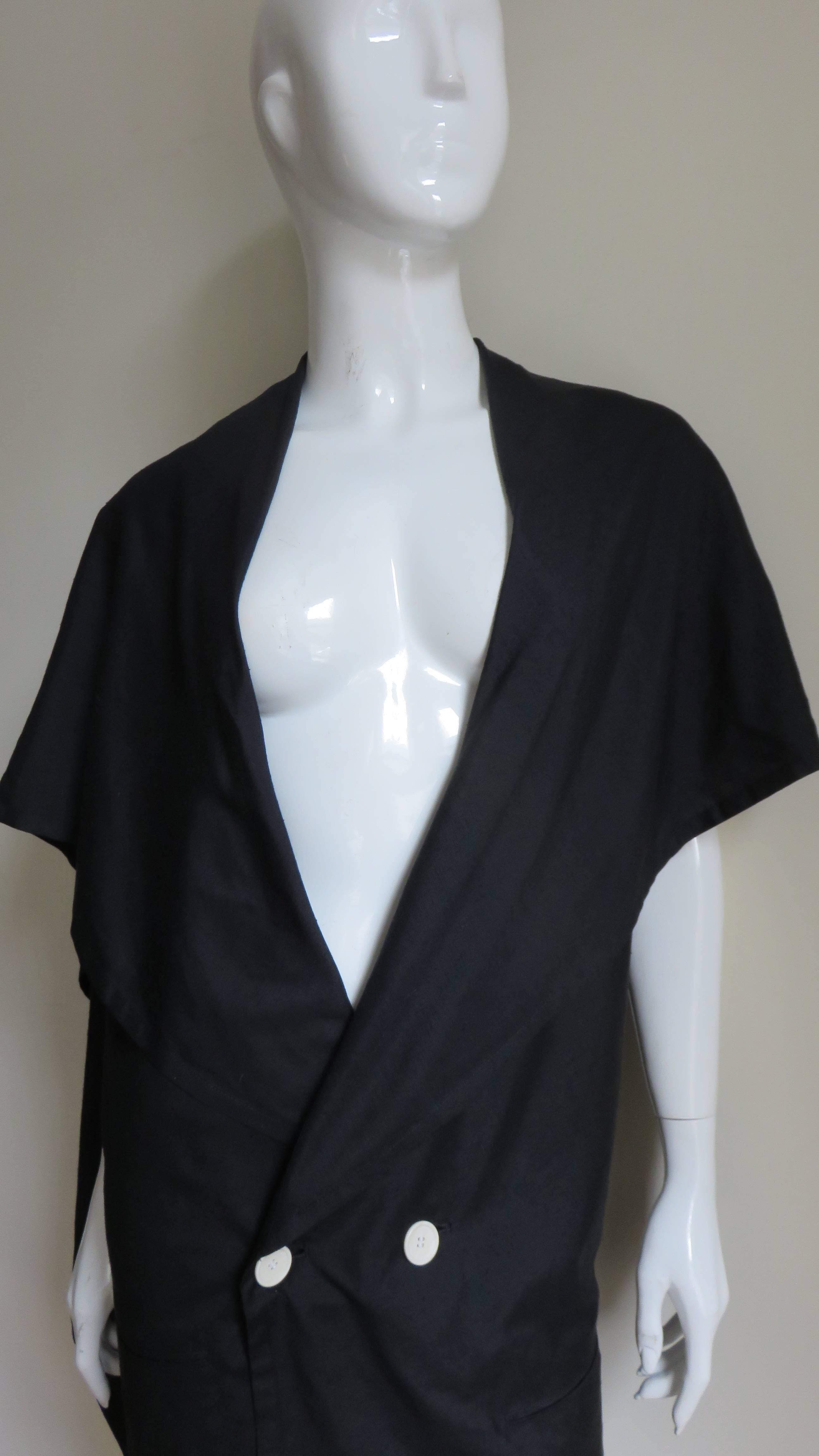 A fabulous black silk jacket from Yohji Yamamoto.  It is double breasted with a collar that asymmetrically drapes over the shoulders and upper arms forming a panel at the back.  It has 2 front hip welt pockets and is unlined.  
Fits sizes Small,