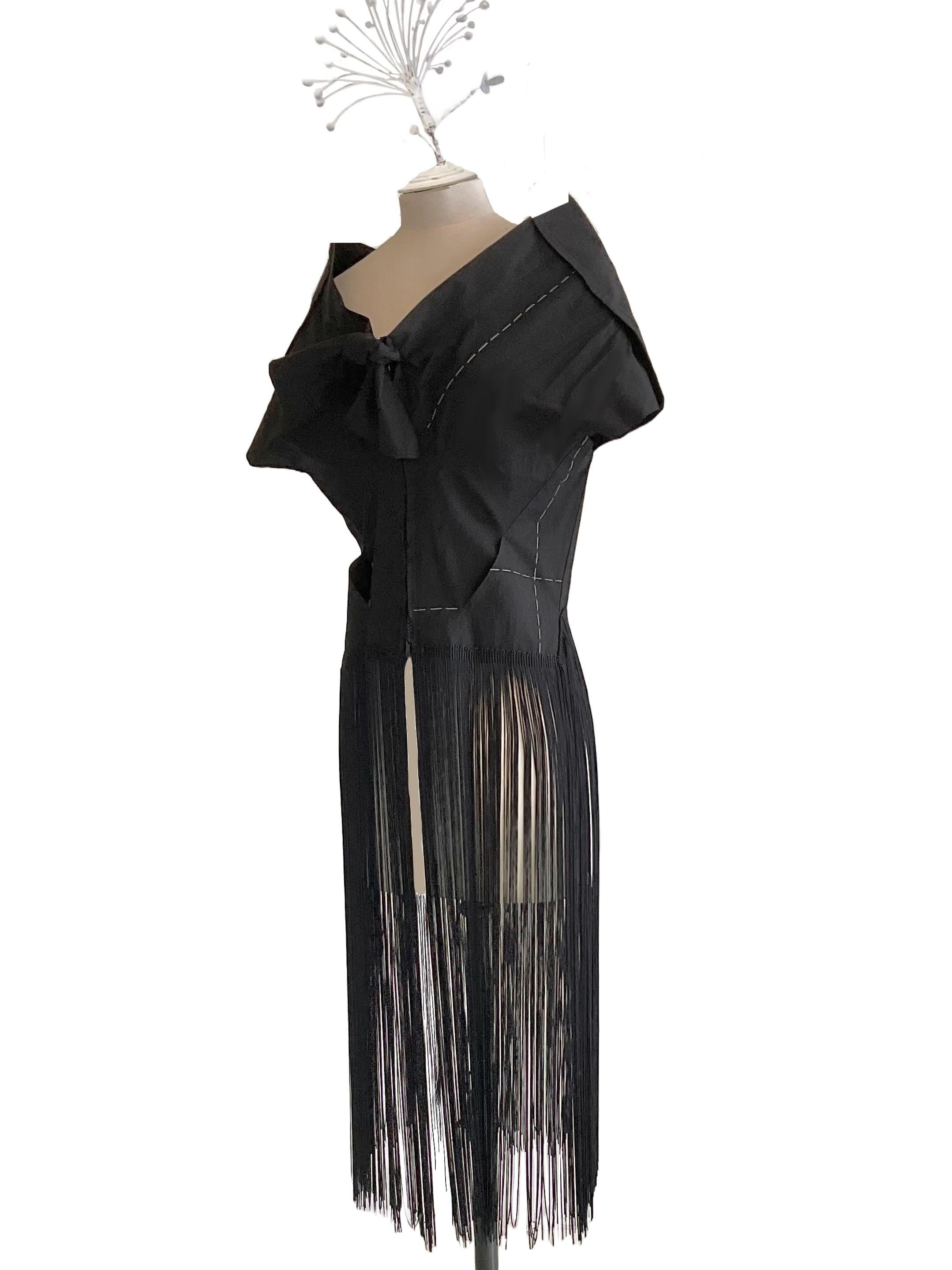 Giacca bolero con frange di Yohji Yamamoto della collezione
Ready to Wear Primavera Estate 2000.
En el centro de la escama, en la parte delantera, se forma un pequeño nudo y desde él
punto vita partono lunghe frange.
Sulla parte sinistra del davanti