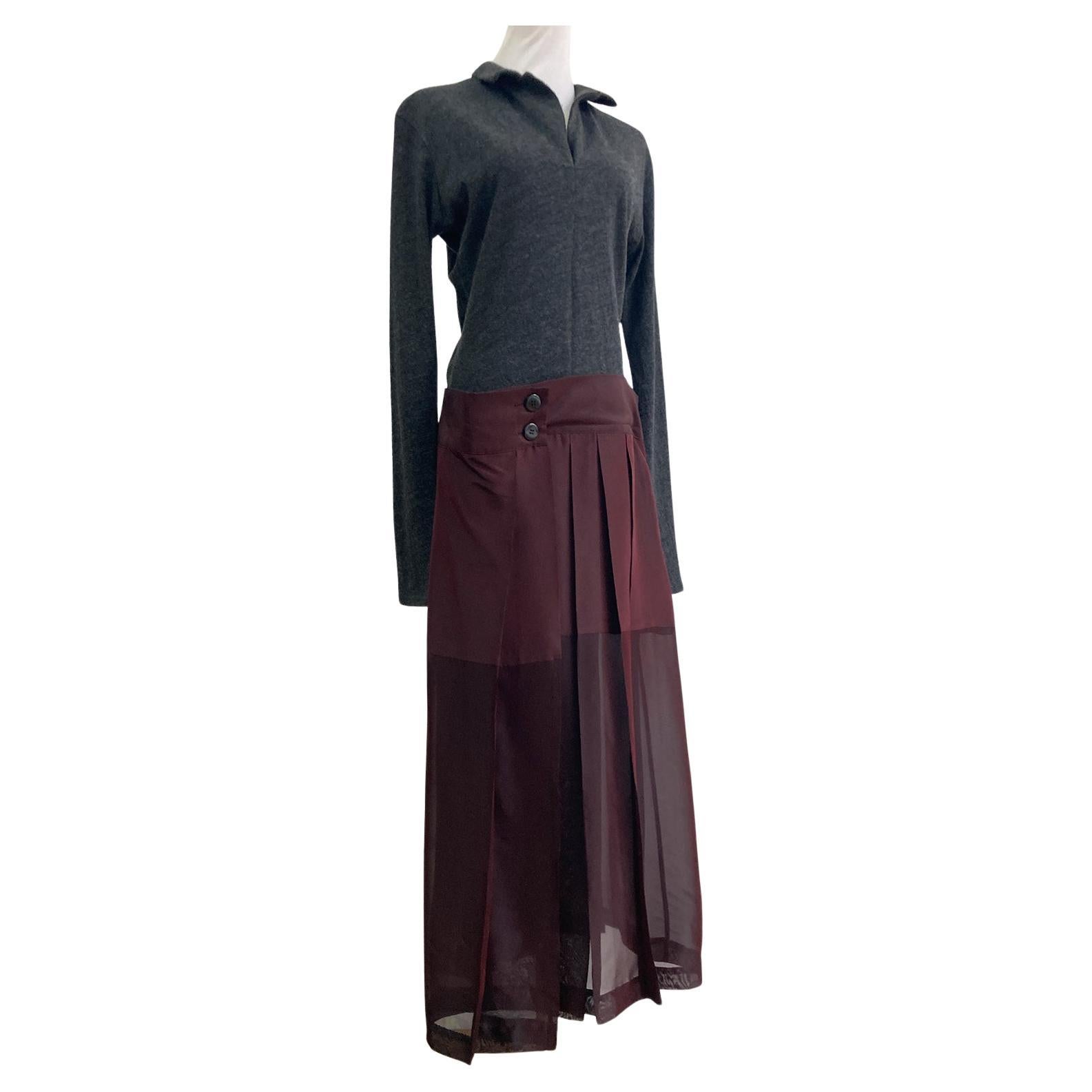 Step back into the collection AW 1995 with this captivating Yohji Yamamoto dress. The design features a unique blend of textures, pairing a soft, grey thin bias cut knit top with a flowing, sheer pleated wrap skirt. The skirt boasts an intriguing,