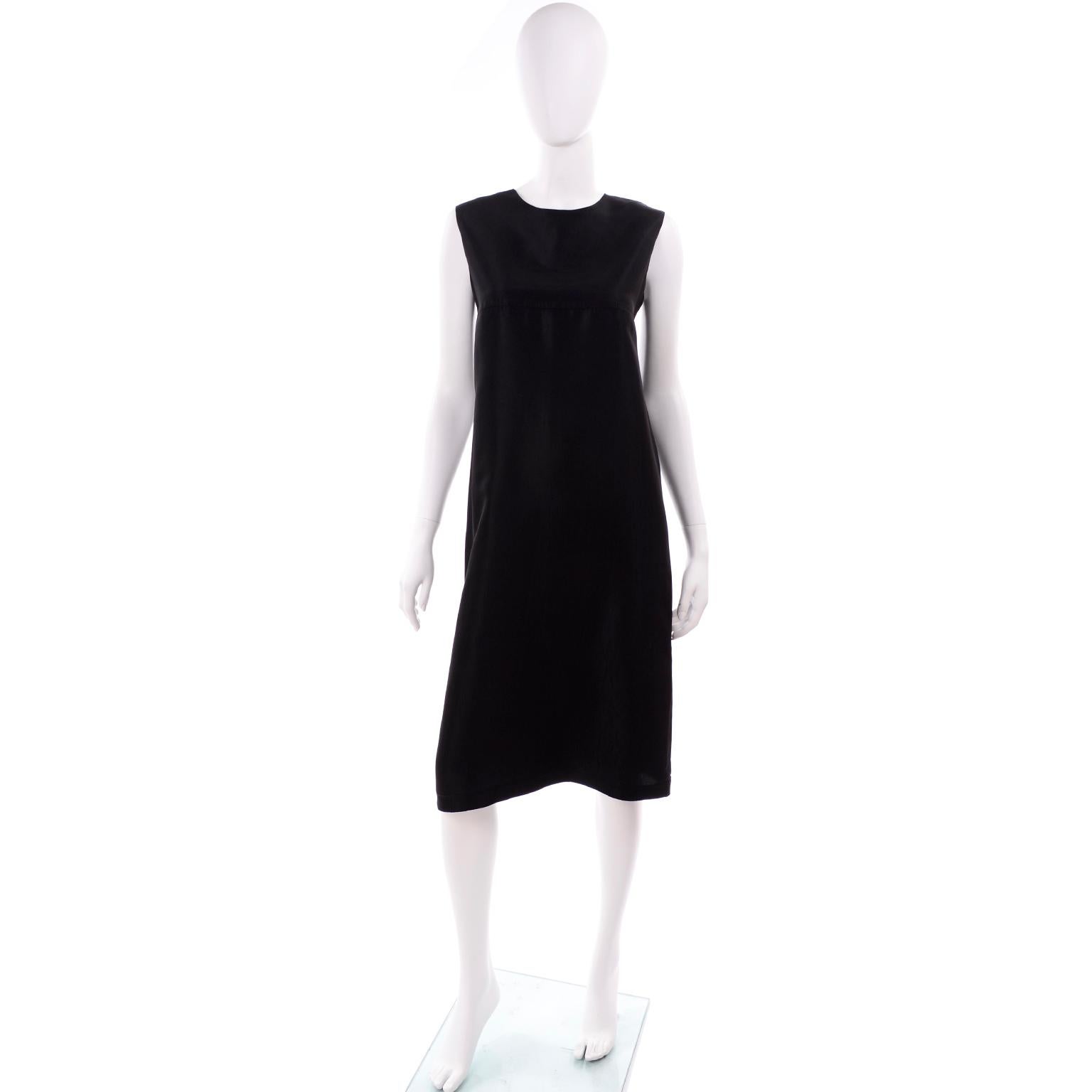 This is a stunning minimalist dress by Yohji Yamamoto +Noir. It is made of a black rayon or silk blend that is sturdy and opaque. The fabric has some subtle texture to it, adding some dimension. It has a seam across the bustline, and has a very