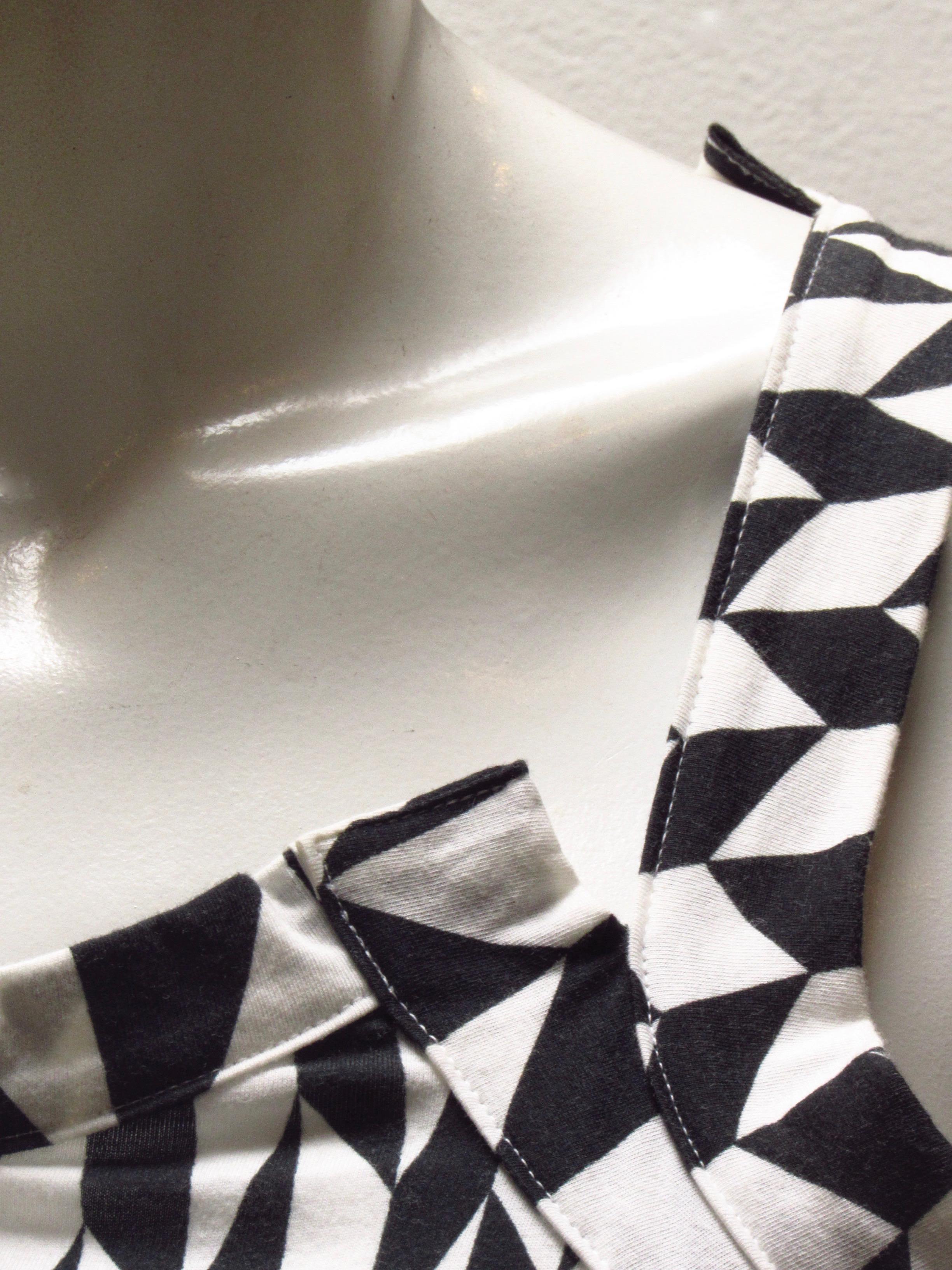 Vintage Yohji Yamamoto Y's tank top features a scoop neckline and racerback cut, both asymmetrical by design. The black and white harlequin pattern courses and changes as it flows across the 100% cotton background.