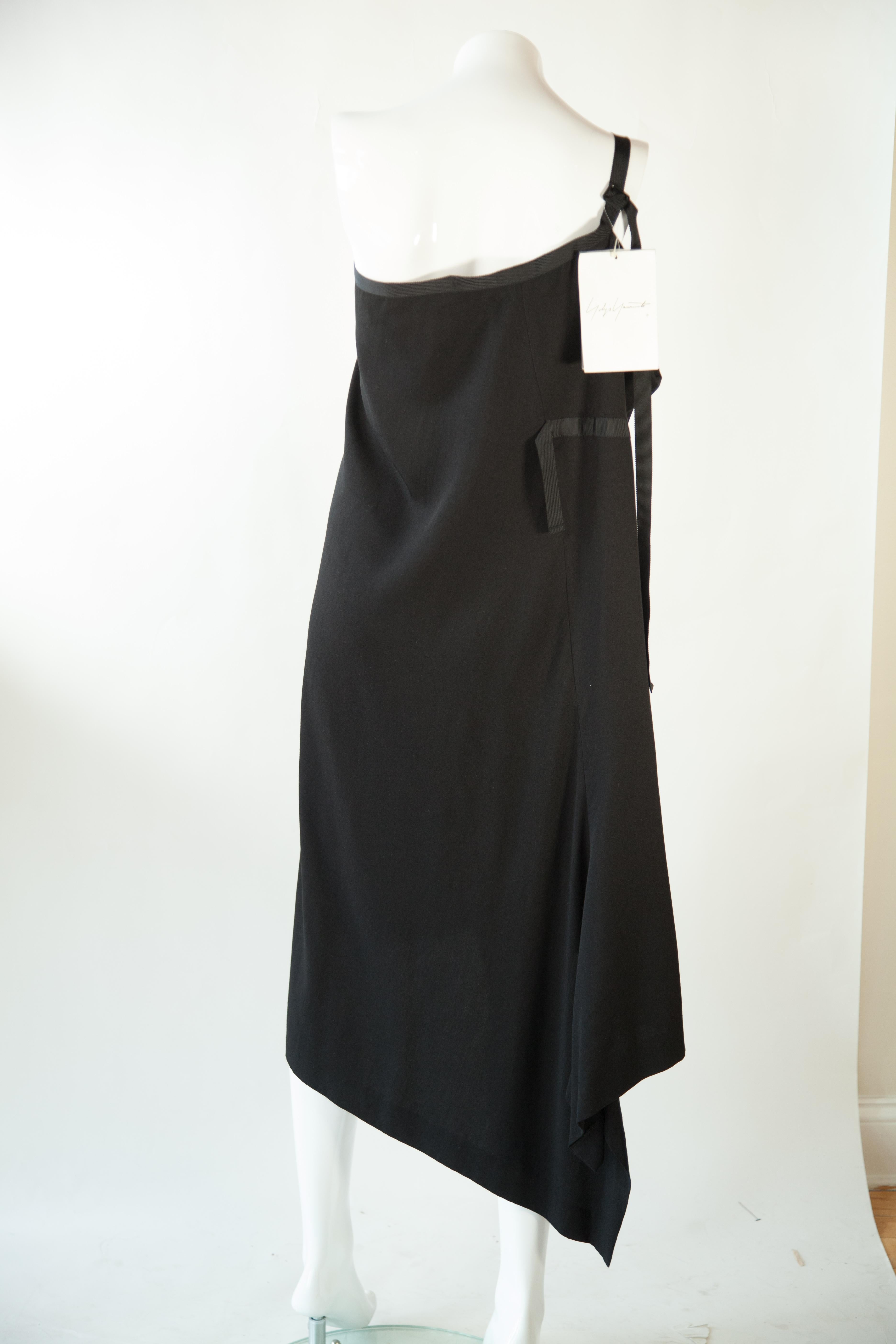 This Yohji Yamamoto black one shoulder dress and skirt combination features an asymmetrical slit for a unique, eye-catching look. The design is timeless, yet fashion-forward, allowing you to stand out from the crowd and make a bold statement.