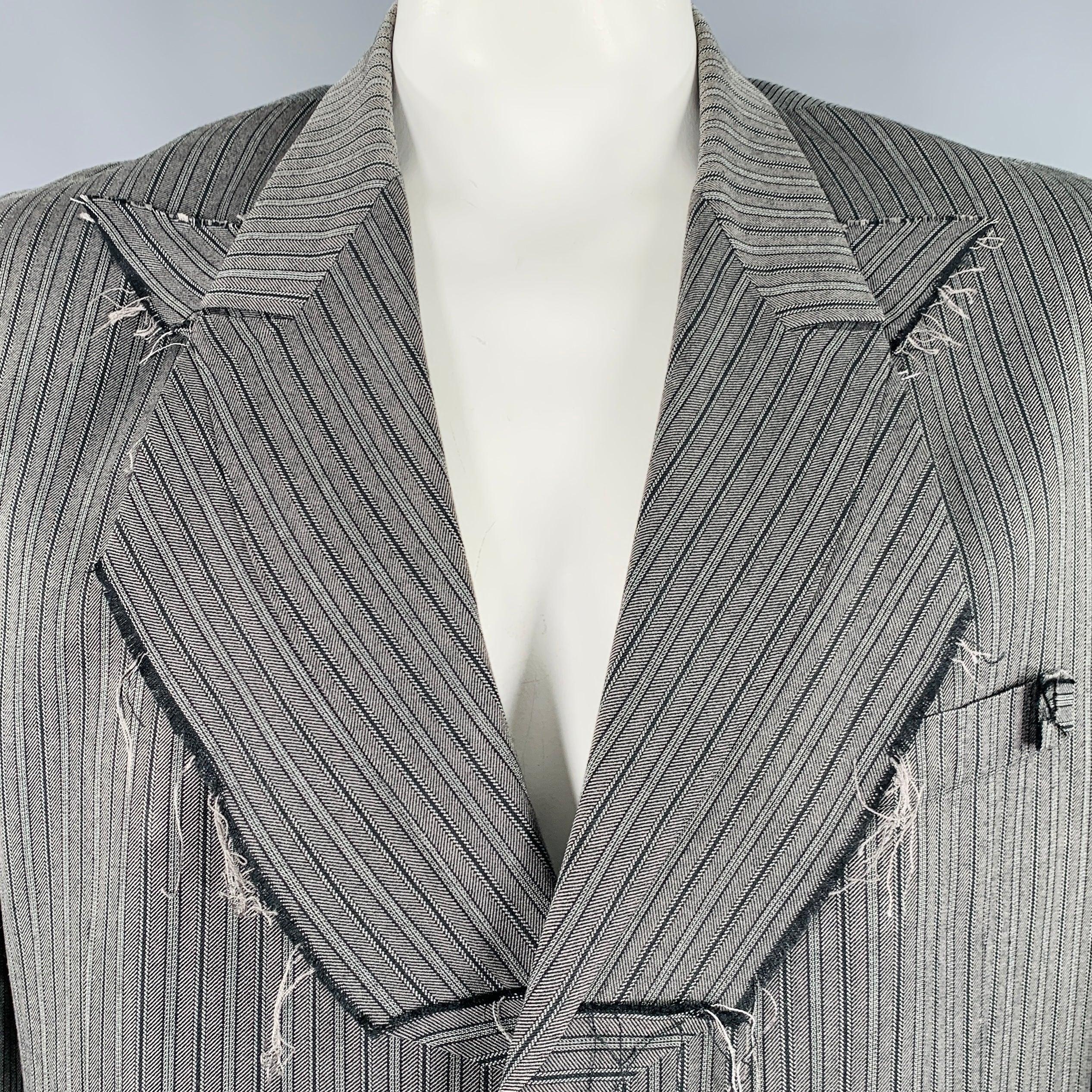 Giacca Yohji Yamamoto
in un 
 in tessuto misto seta grigio e nero con motivo a righe, bavero decostruito, vestibilità oversize, bordi grezzi e chiusura a tre bottoni. Made in Japan.Ottime condizioni di usato. Riparazioni di fori minori sul polsino,