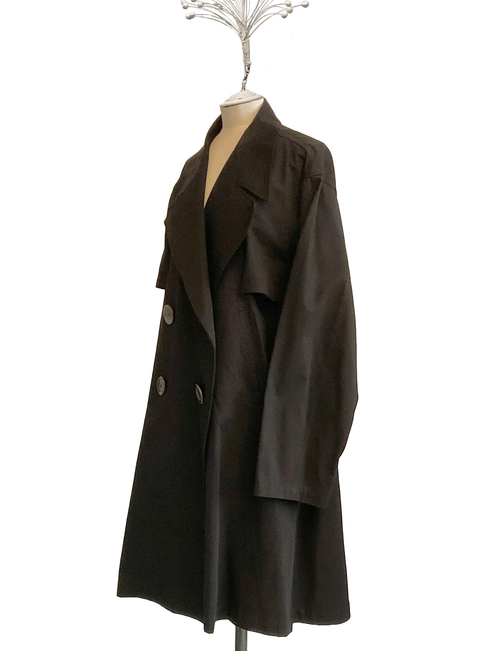 Trench nero doppiopetto con martingala probabilmente in cotone di
Yohji Yamamoto de los primeros años 2000.
Il capo ha grandi revers e quattro bottoni giganti, le tasche sono
laterali a filetto.
Por debajo del giratorio, en la parte delantera, hay