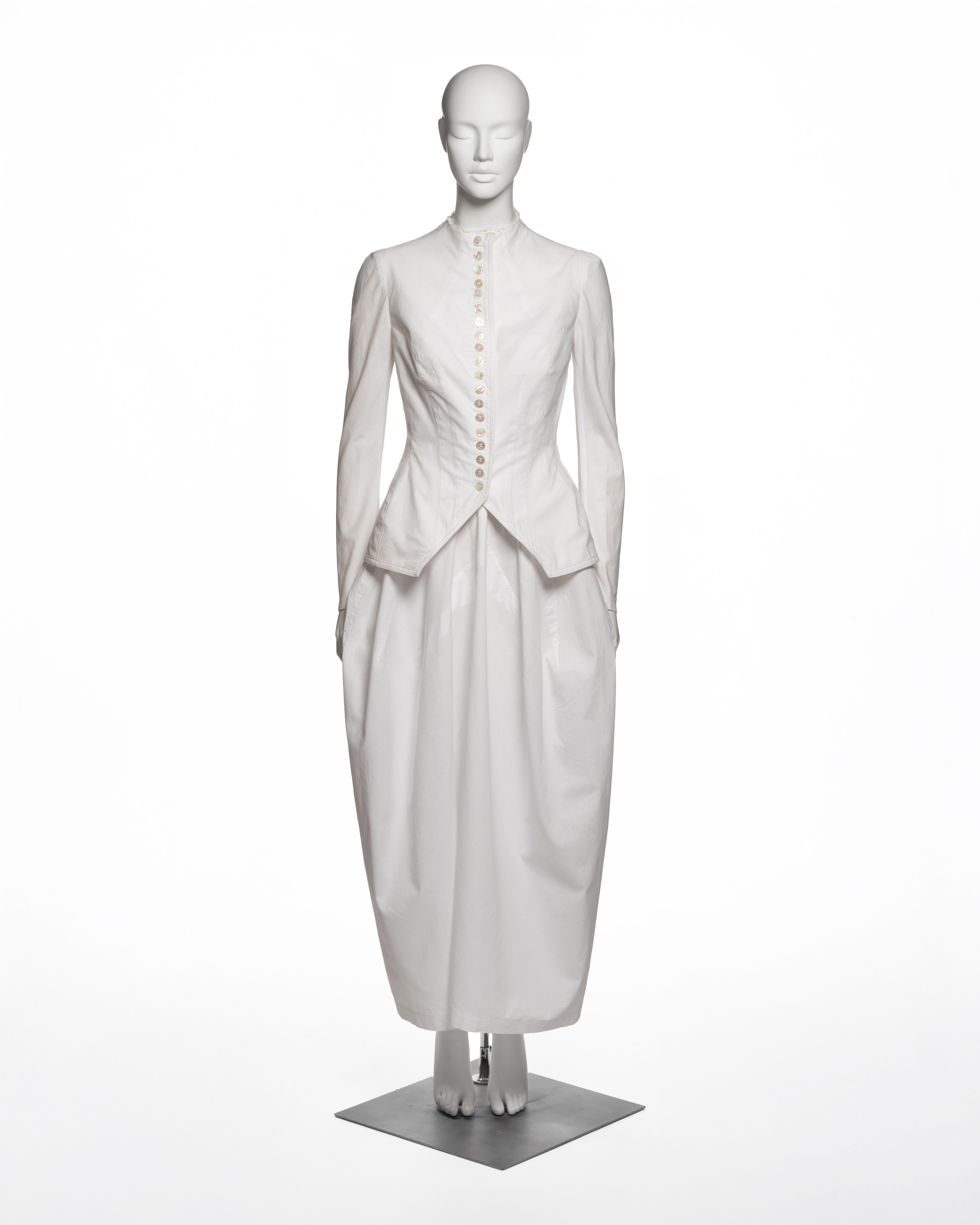 Yohji Yamamoto, primavera-estate 1998: Completo a due pezzi in cotone bianco, composto da una giacca a maniche lunghe dal taglio deciso e da una gonna a tulipano a vita alta. La giacca ha un corpetto aderente con pinces e un pronunciato orlo a peplo
