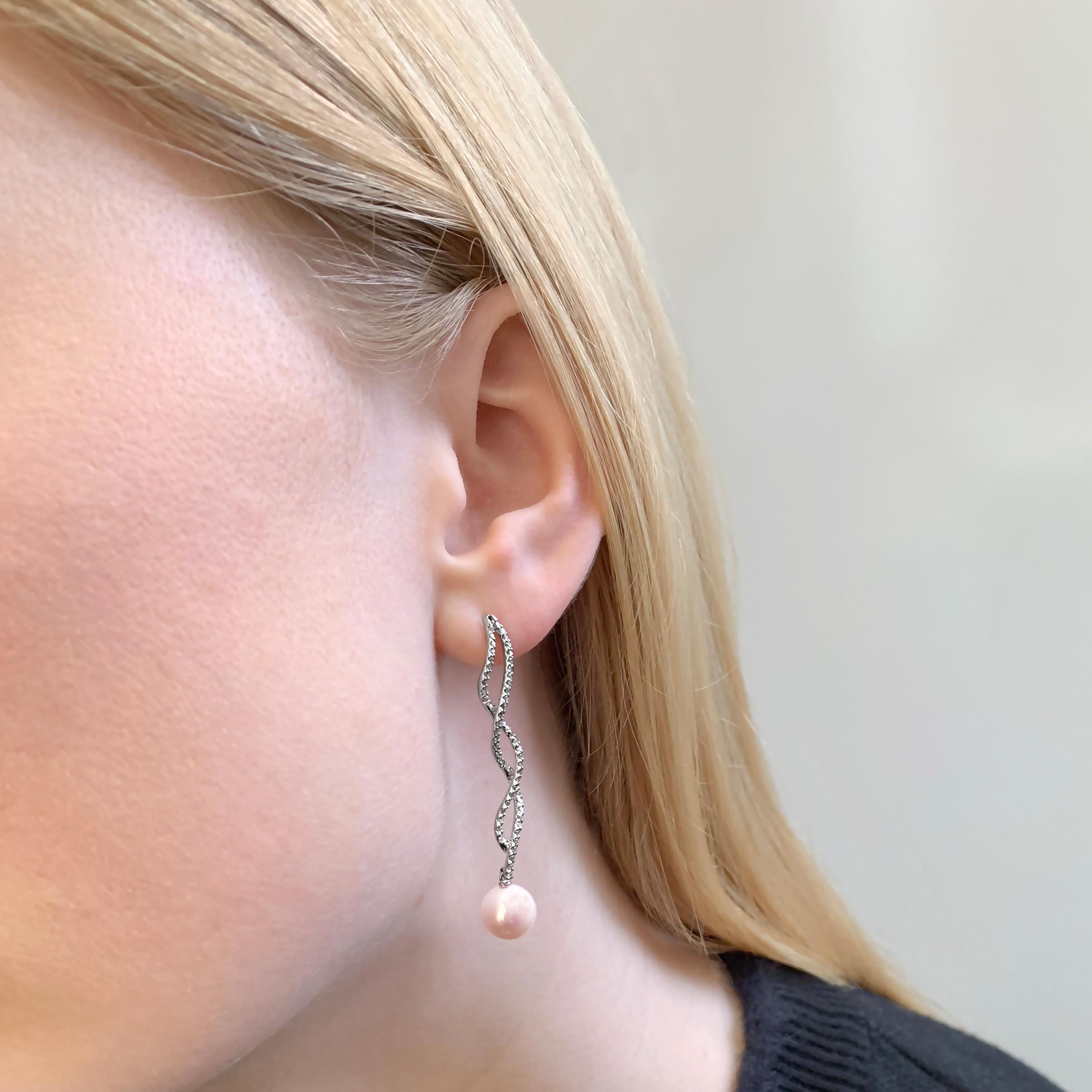 These elegant earrings by Yoko London feature Freshwater pearls beneath a delicate twist of diamonds. The 18 Karat white gold setting perfectly enriches the lustre of the pearl and the bright sparkle of the diamonds. The length of these earrings