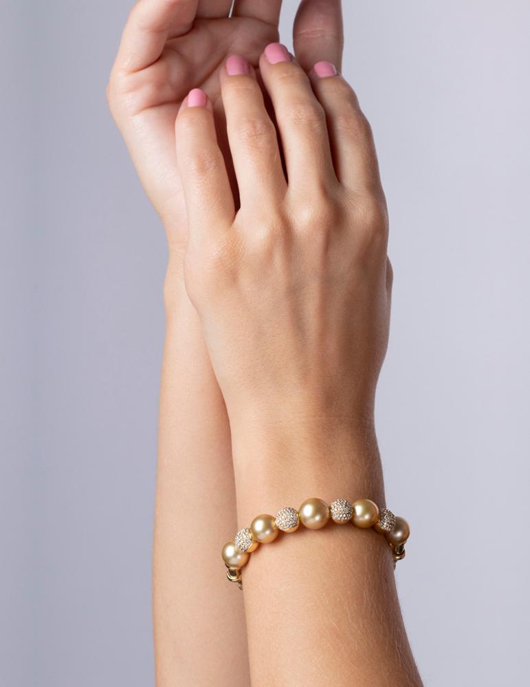 Ce bracelet unique présente de somptueuses perles dorées des mers du Sud de 9-10 mm enchâssées entre des sphères de diamants scintillants. Serti en or jaune 18 carats pour compenser les riches tons dorés des perles, ce bracelet spectaculaire est