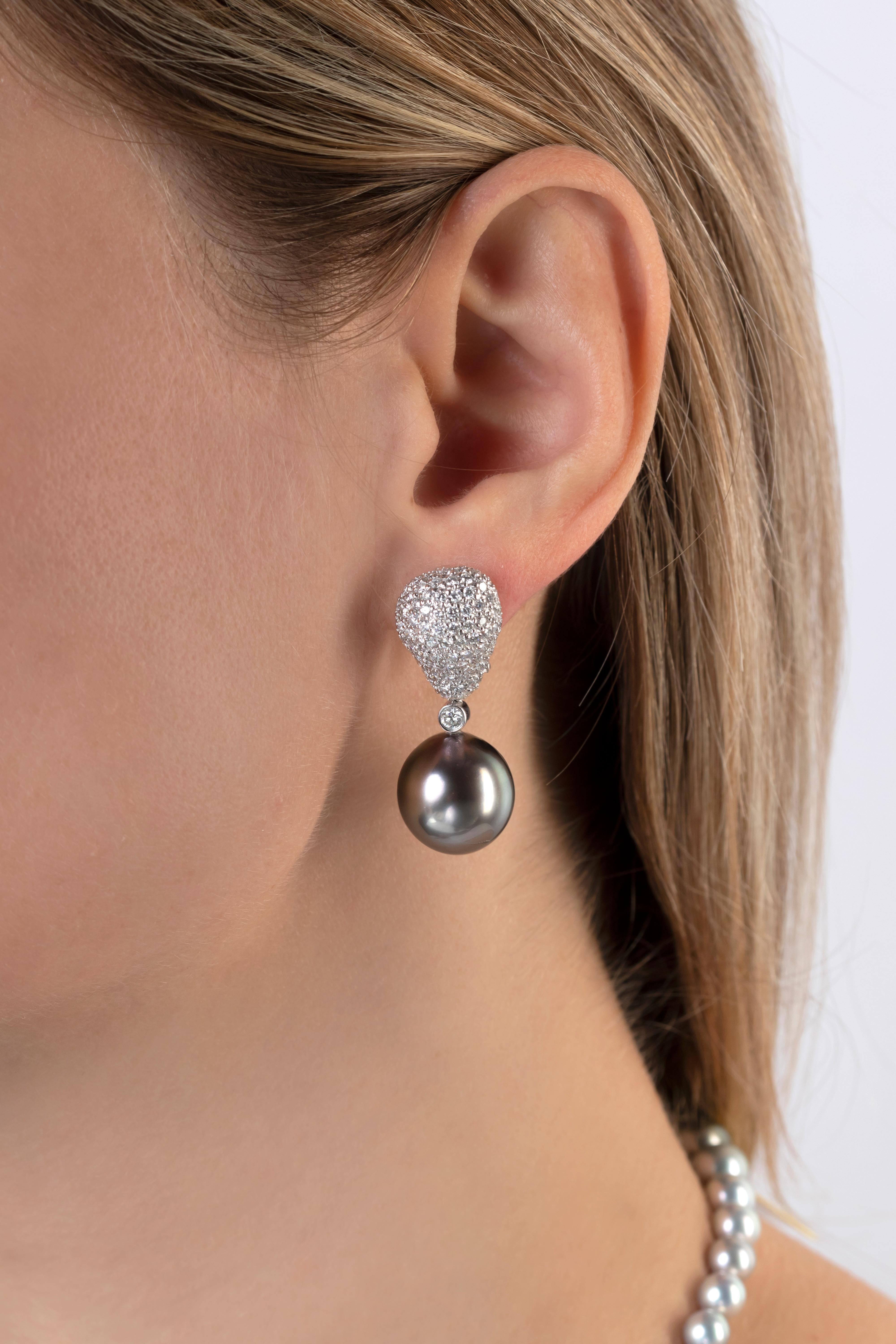These striking earrings by Yoko London feature 15.5mm Tahitian pearls beneath a scintillating arrangement of pavé-set diamonds. The 18 Karat white gold setting perfectly accentuates the excellent lustre and natural colour of the Tahitian pearls.