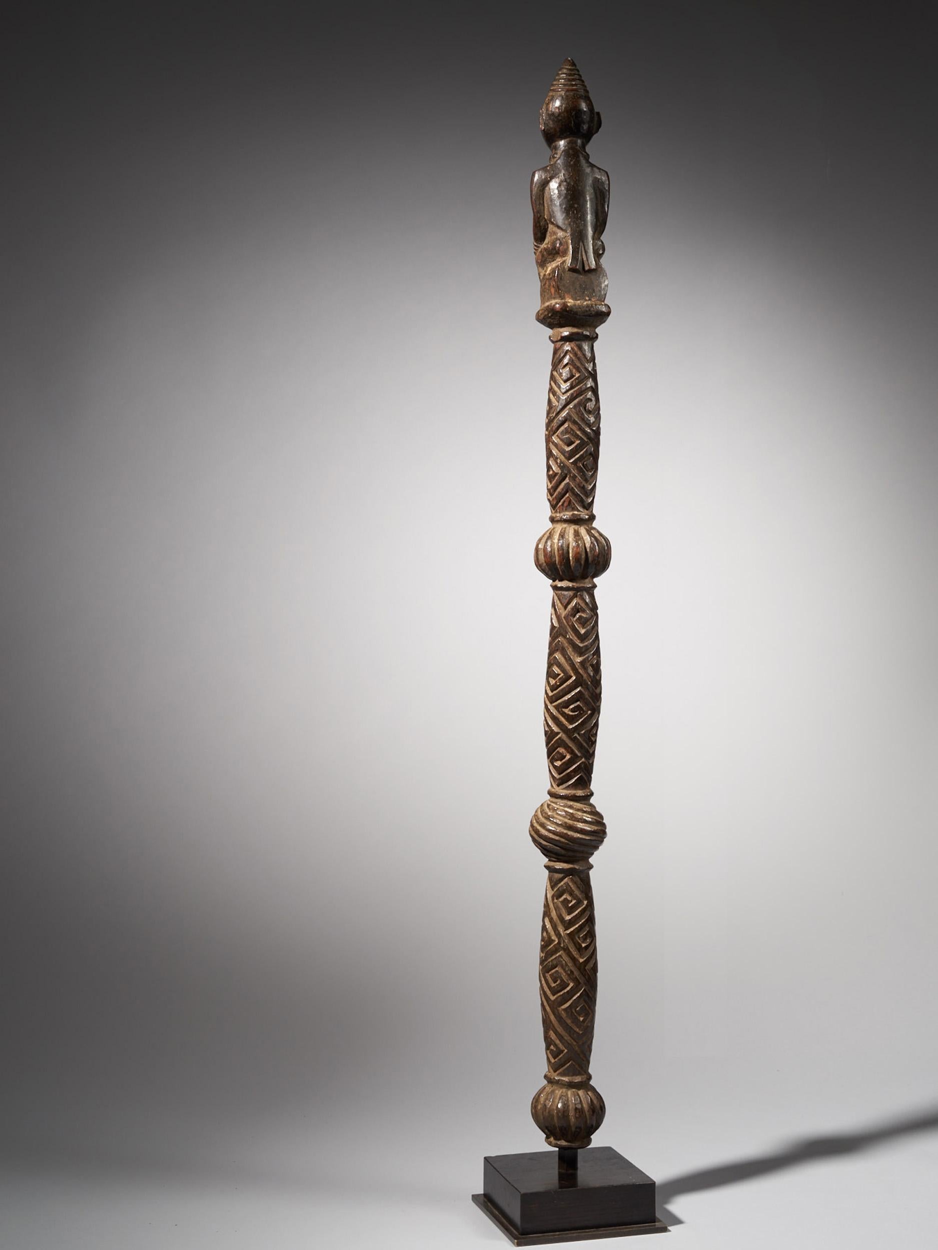 A Wooden Yombe Mwaala Chief Staff, with three globular elements. The Finial is a finely carved female figure kneeling, the hands resting on the knees and with raised scarification marks above the prominent breasts. The head carved powerfully with