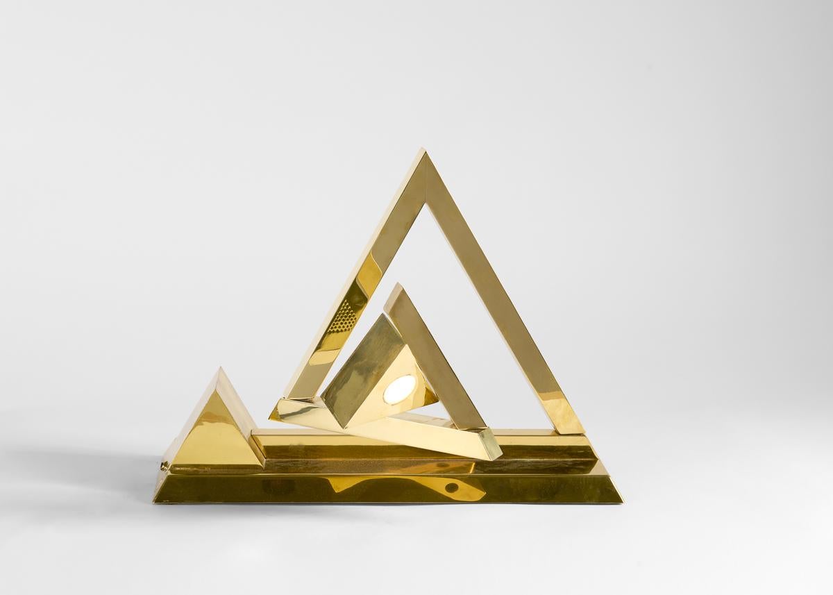 Lebovici's training in physics is clear in this remarkable, wholly unique lamp. The pyramidal piece is composed in a spiraling series of lineal brass elements, each of which moves on hinges, allowing its center to extend toward or away from an