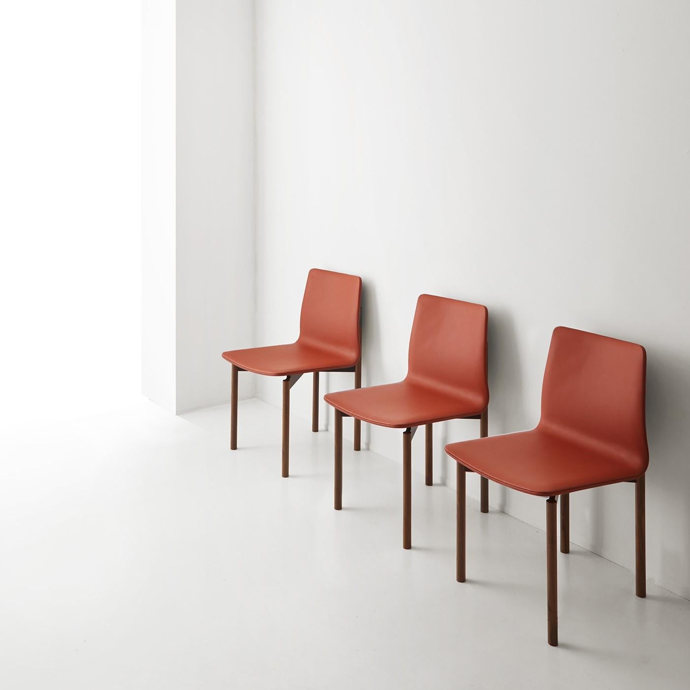 Der Stuhl mit einer essentiellen Form ist aus massivem Walnussholz gefertigt und mit Leder bezogen. Die Besonderheit dieses Stuhls liegt in der Holzbearbeitung der Rückenlehne und in seiner Größe. Er ist in verschiedenen Lederfarben und anderen