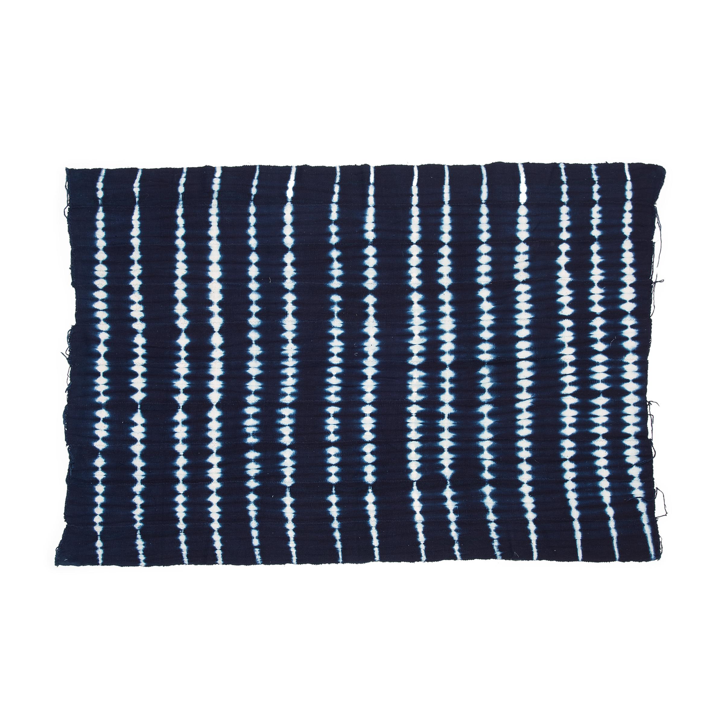 A vibrant and beautifully irregular pattern covers this indigo textile by the Yoruba people of Nigeria. Hand-dyed by women, this style of tie-resist indigo cloth is known as adire oniko and is achieved by tightly tying up portions of the strip-woven