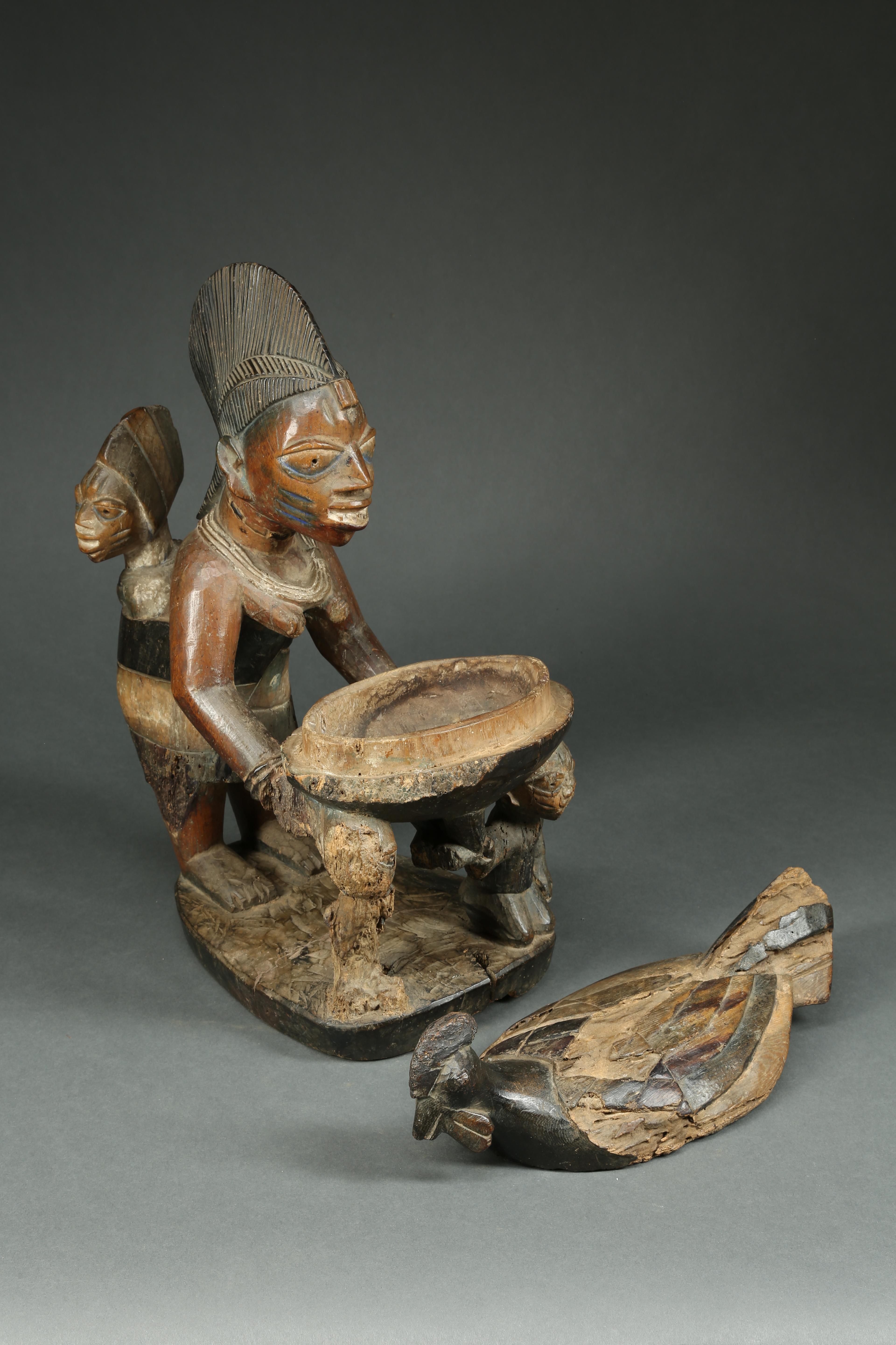 Blessed by time, an early beautiful Yoruba female figure with baby riding on back, presenting an offering bowl in the form of a chicken with a removable top. Great Yoruba mother's face with scarifications and an excited baby. Areas of heavy wear,