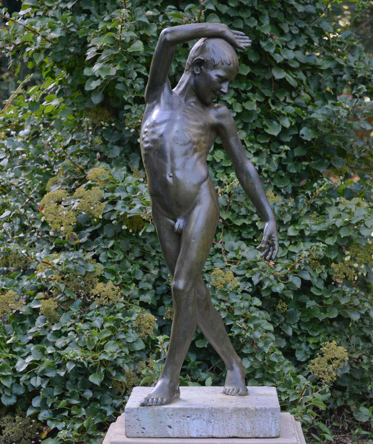 An exceptional bronze figure of a youth portrayed as nude and standing in a fluid pose, the face with jubilant expression and downward gaze, with one arm upswept and the other down, with one leg crossed in front of the other, suggesting movement,