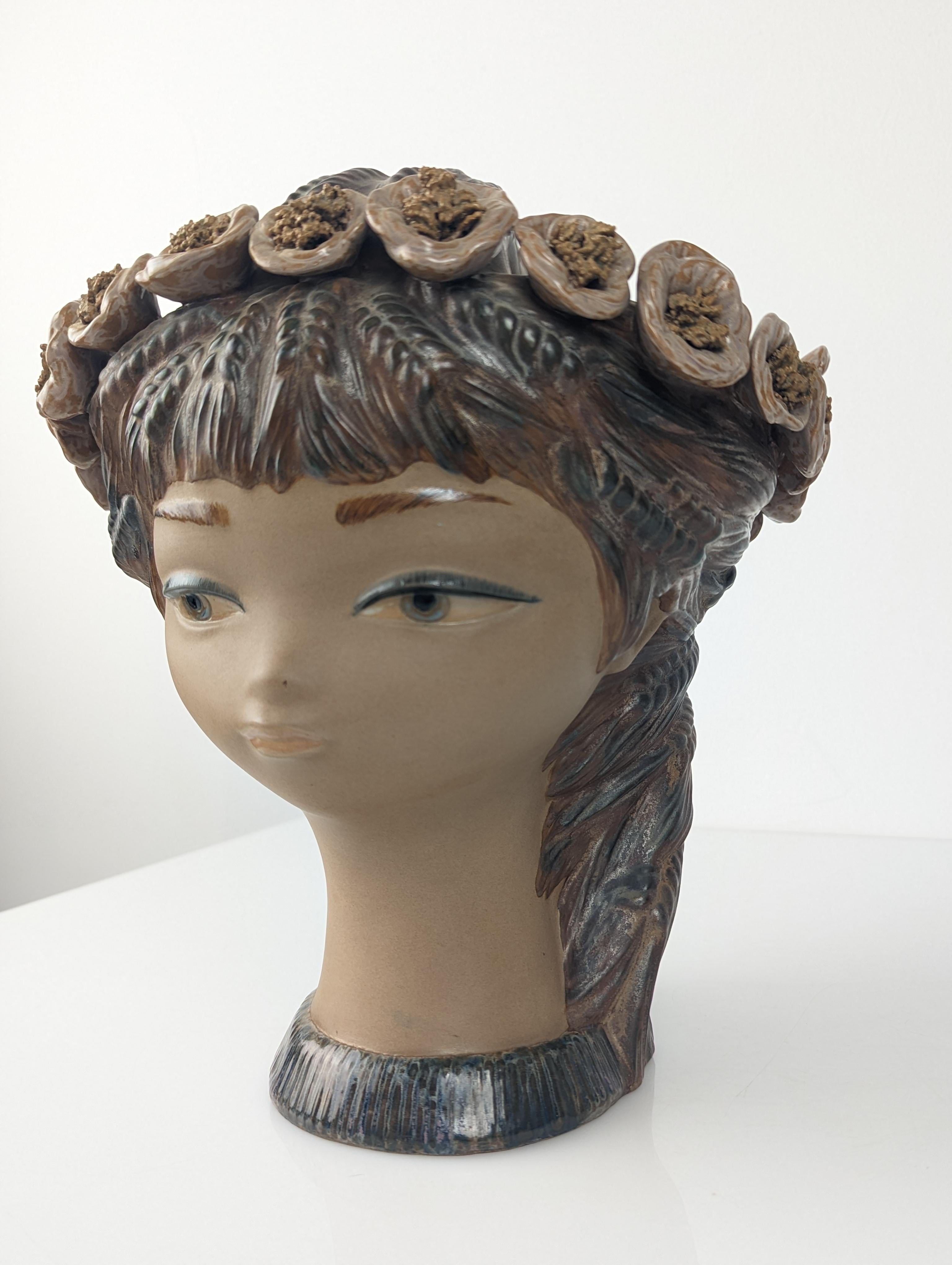 Precious vase with handle, design created by Vicente Martínez for Lladro in its rarest version, made in stoneware in 1971. This beautiful collection piece represents a beautiful young woman with a calm gaze, hair with spikes and a crown of poppies