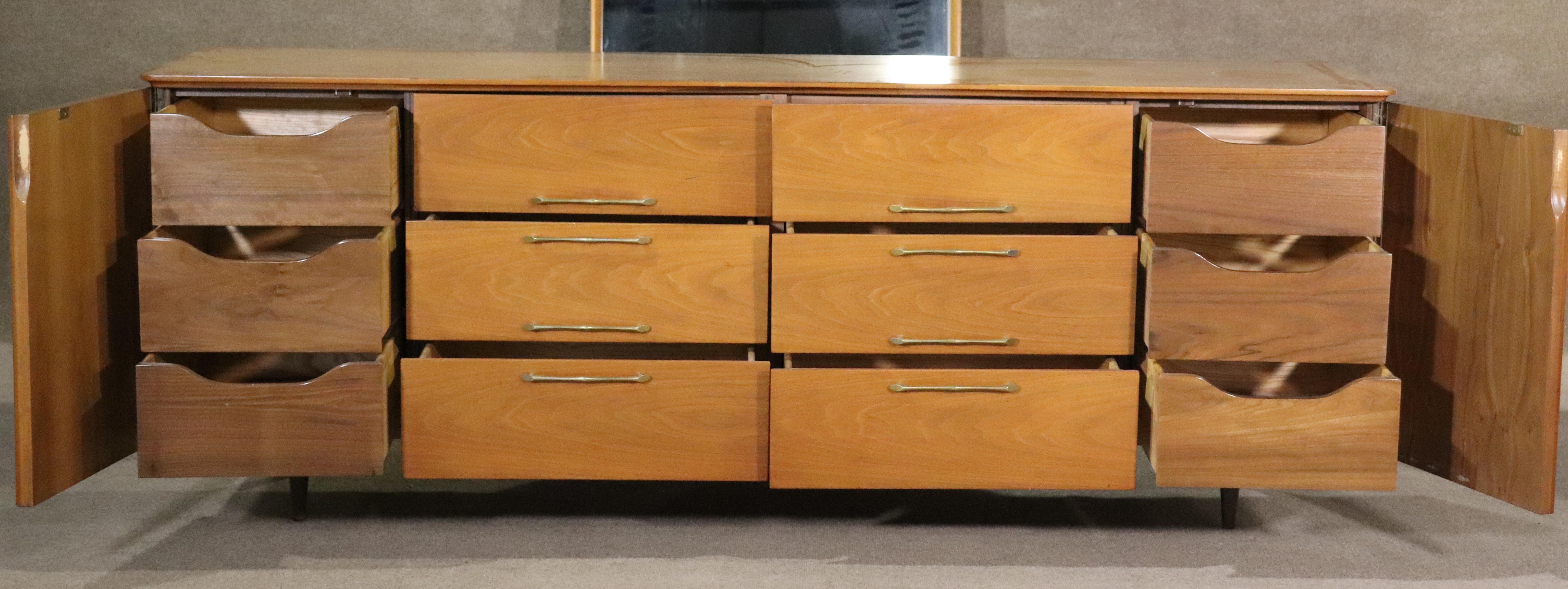 Long twelve drawer dresser in walnut with brass hardware. Sculpted doors, tapered feet and a cut out top. Mirror is included.
Mirror: 31.25h, 49.25w
Please confirm location NY or NJ