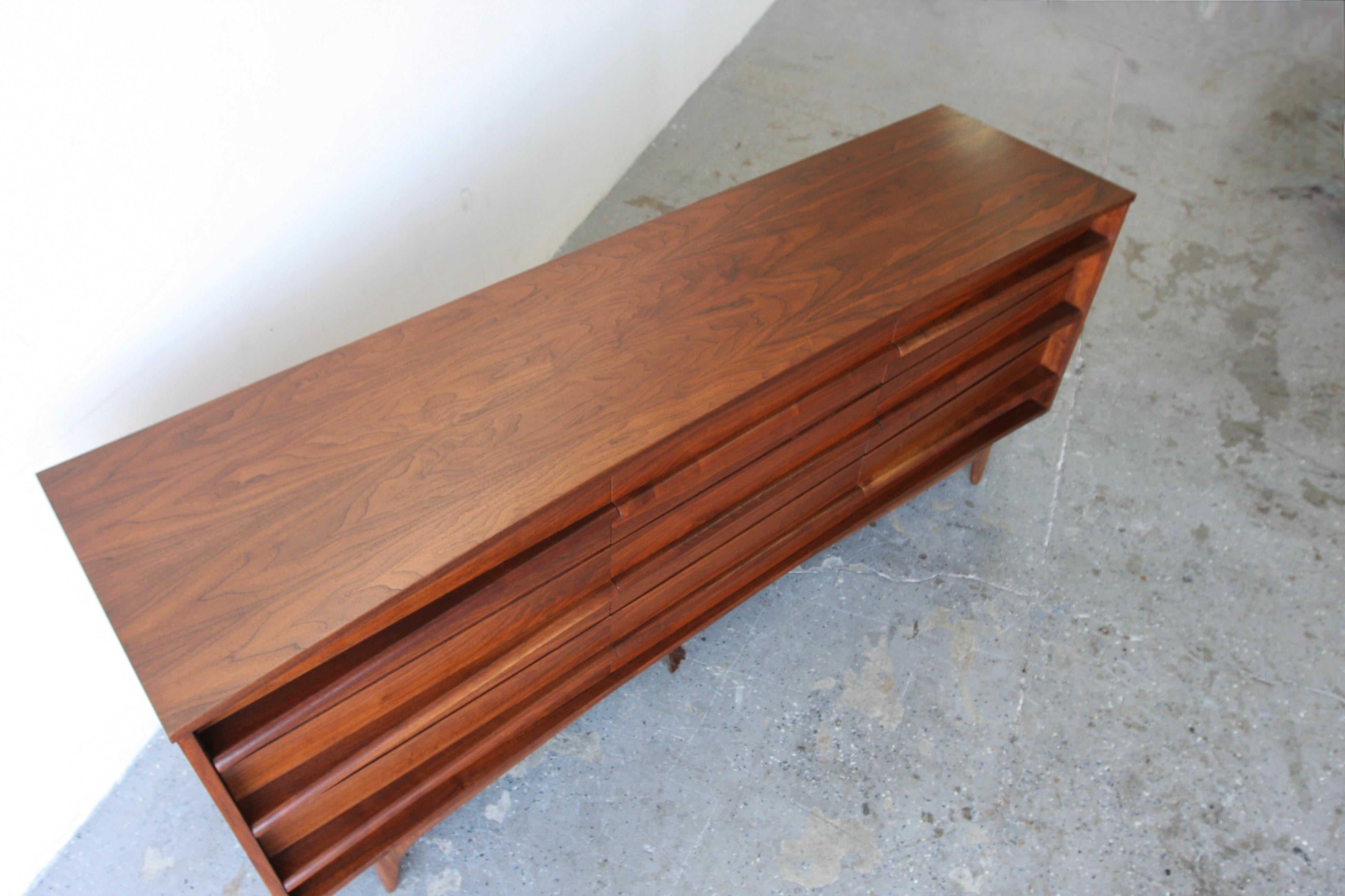 Young Manufacturing Mid Century Walnut Curved Lowboy 9 Drawer Dresser

Sculpted walnut pulls extend the full length of the credenza, tapering in the middle and expanding again towards the end, creating a sense of unity throughout the piece. The body