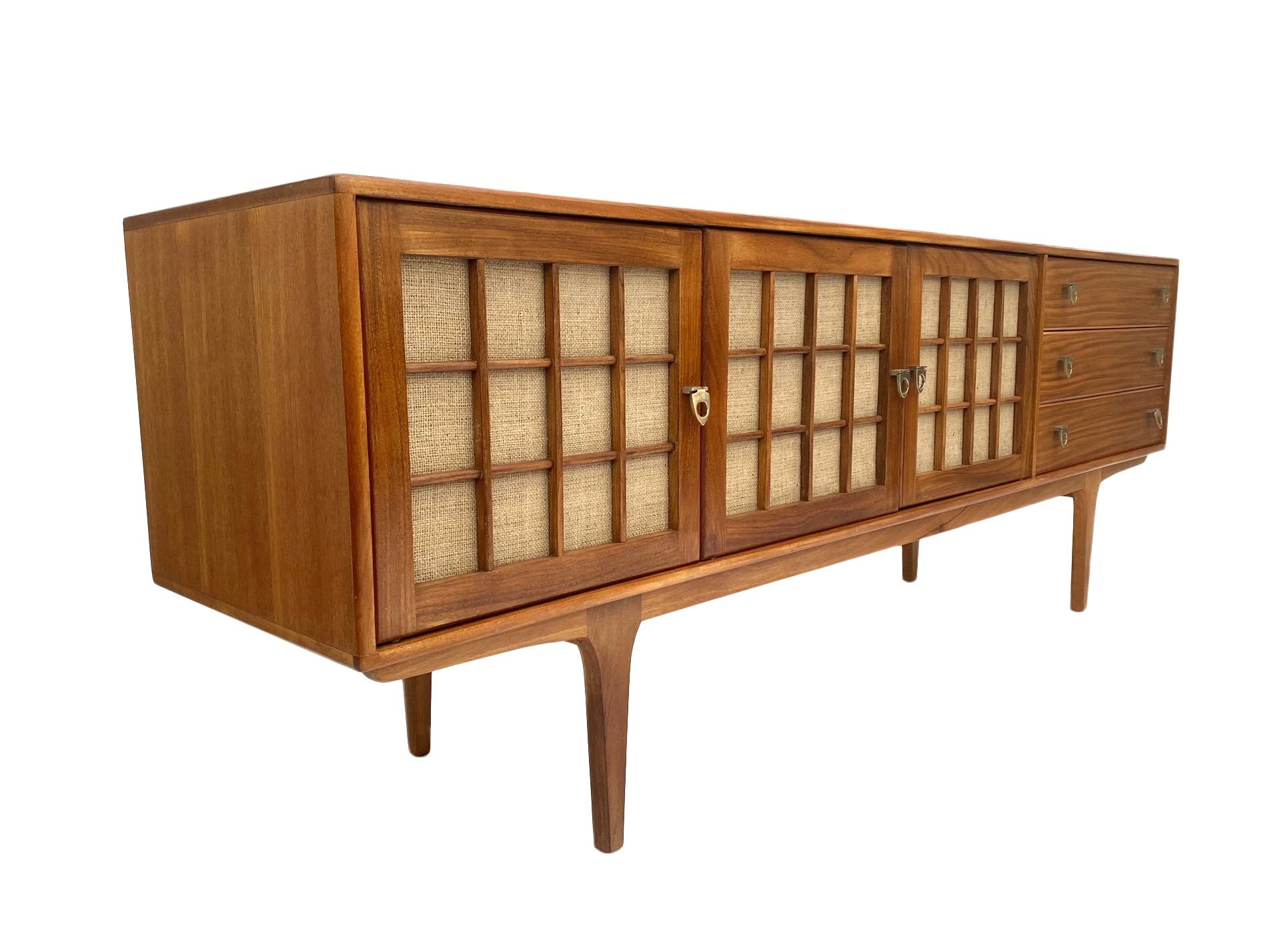 A beautiful British long teak sideboard by Younger, this would make a stylish addition to any living or work area.

The cabinet has three cupboards with a shelf to the left and a bank of four drawers to the right, all are in good order with