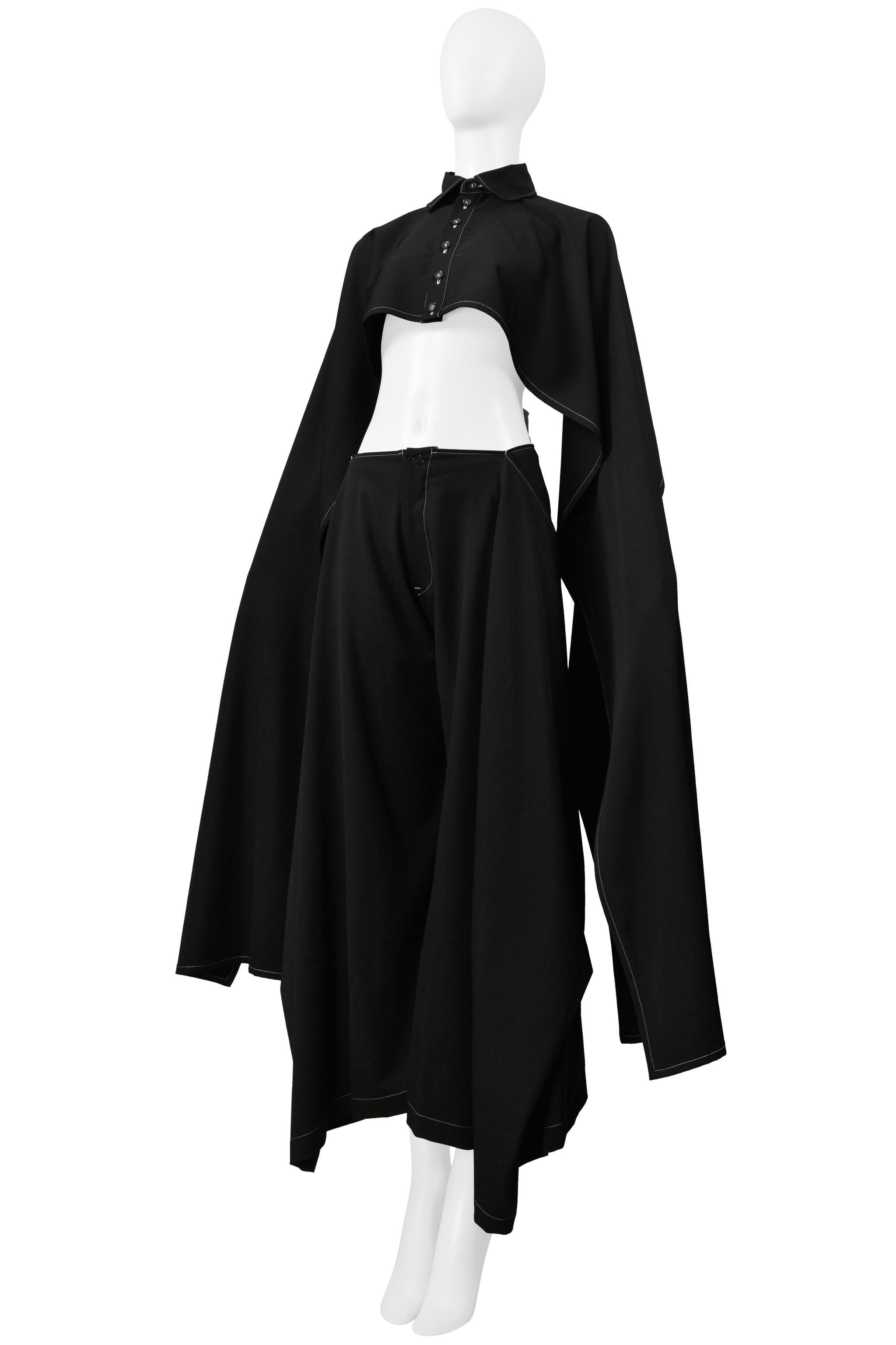 Resurrection Vintage is excited to present a vintage Y's by Yohji Yamamoto black cape and pants ensemble with white stitching. The ensemble features a cropped cape with a high neck collar, front buttons, and long billowing sleeves; the pants have