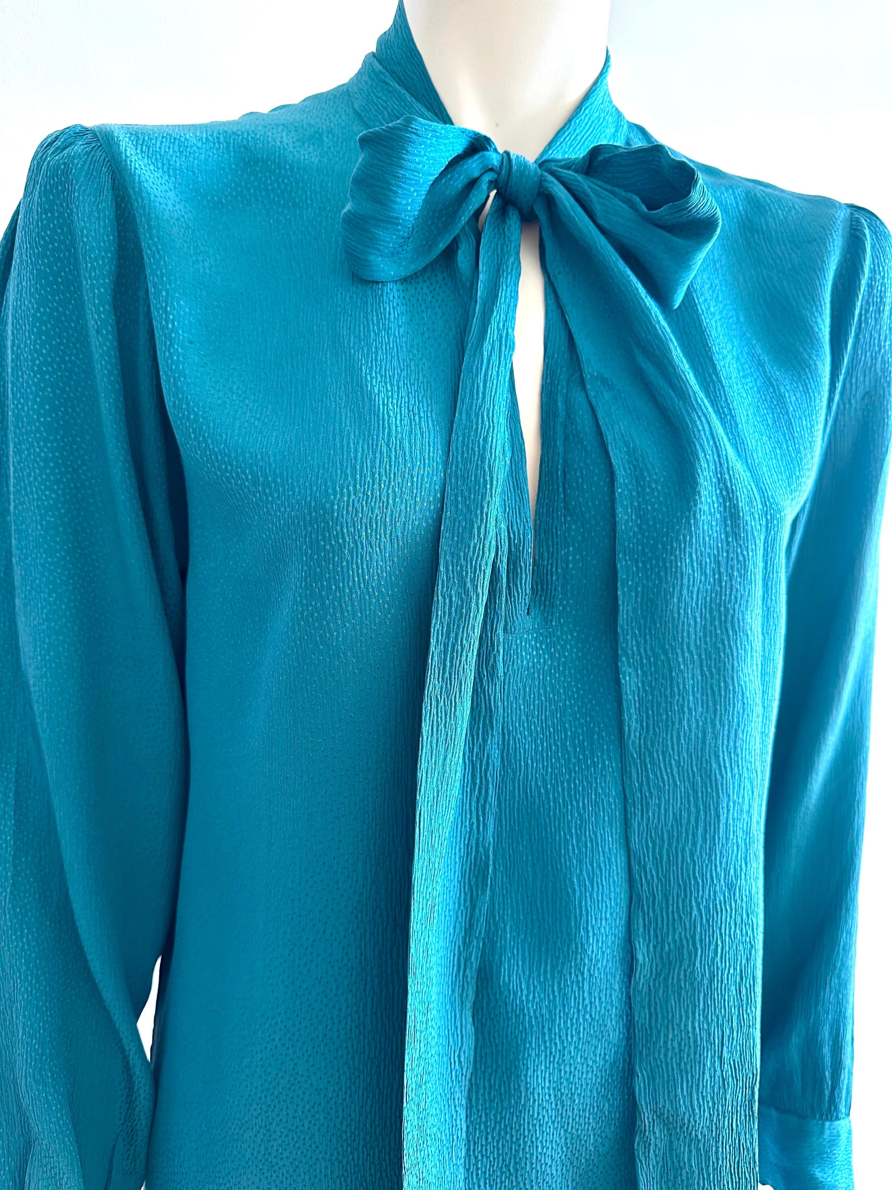 Yves saint Laurent Rive gauche lavallière collar blouse from the 1970s.
In duck-blue silk, this pretty blouse features a lavallière collar with an opening on the chest.
The shoulders are slightly gathered, the sleeves are long and closed with a