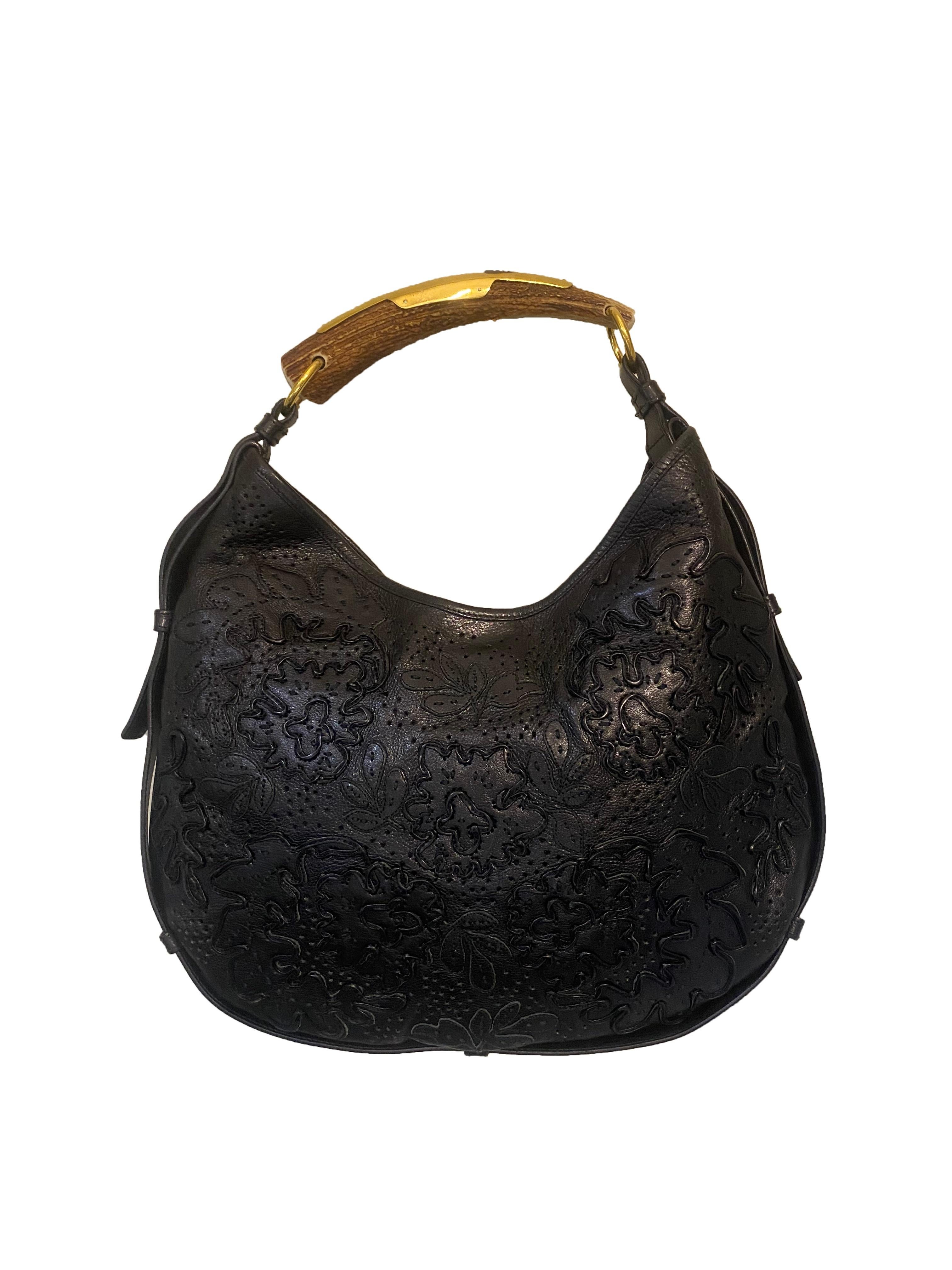 Vintage black leather special edition Mombassa bag from Yves Saint Laurent Rive Gauche. Circa 1999 - 2003 Tom Ford era YSL. Crescent shape body in black leather with perforations and embellished with floral applique leather detail. Single horn top