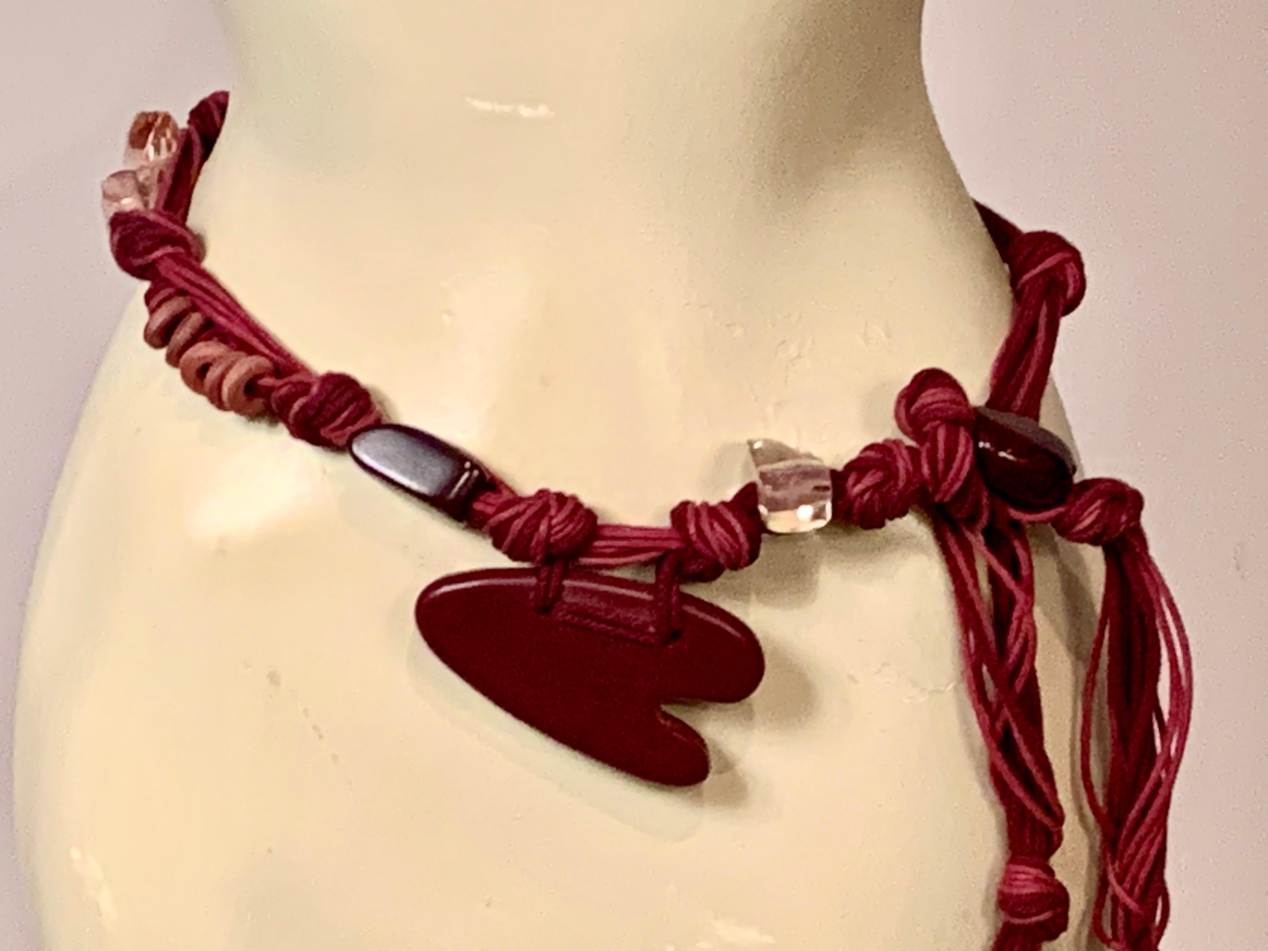 Si tratta di una divertente cintura degli anni '70 con attribuzione YSL da parte della proprietà. La cintura in corda è impreziosita da un grande cuore in legno e da pietre lucide di colore bordeaux e rosa pallido. Le corde sono in diverse tonalità