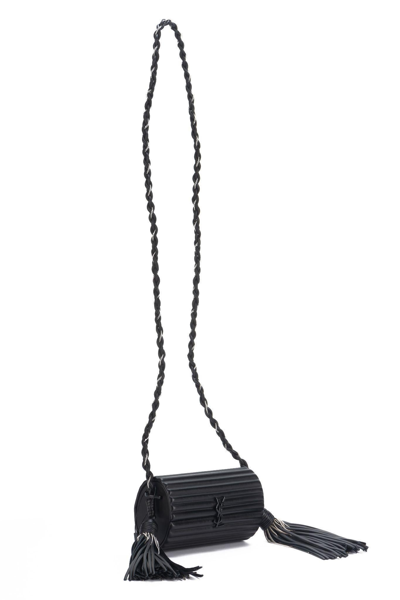 Yves Saint Laurent crossbody black leather ribbed barrel bag, two leather and gunmetal chain tassels. Shoulder drop 22.5”. Original price $2580. Comes with booklet and original dust cover.