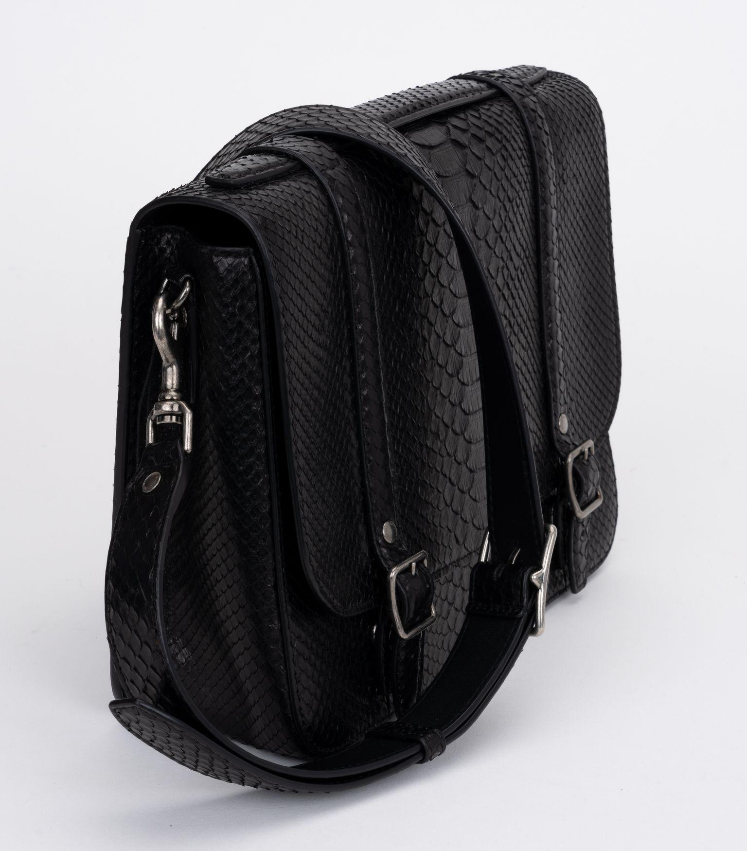 YSL new black brushed python schoolbag. Top handle, buckle fastenings, an  internal zipped pocket, a front embossed stamp, a back zip pocket and a detachable shoulder strap. Comes with original dust cover. 
Store price $3150.