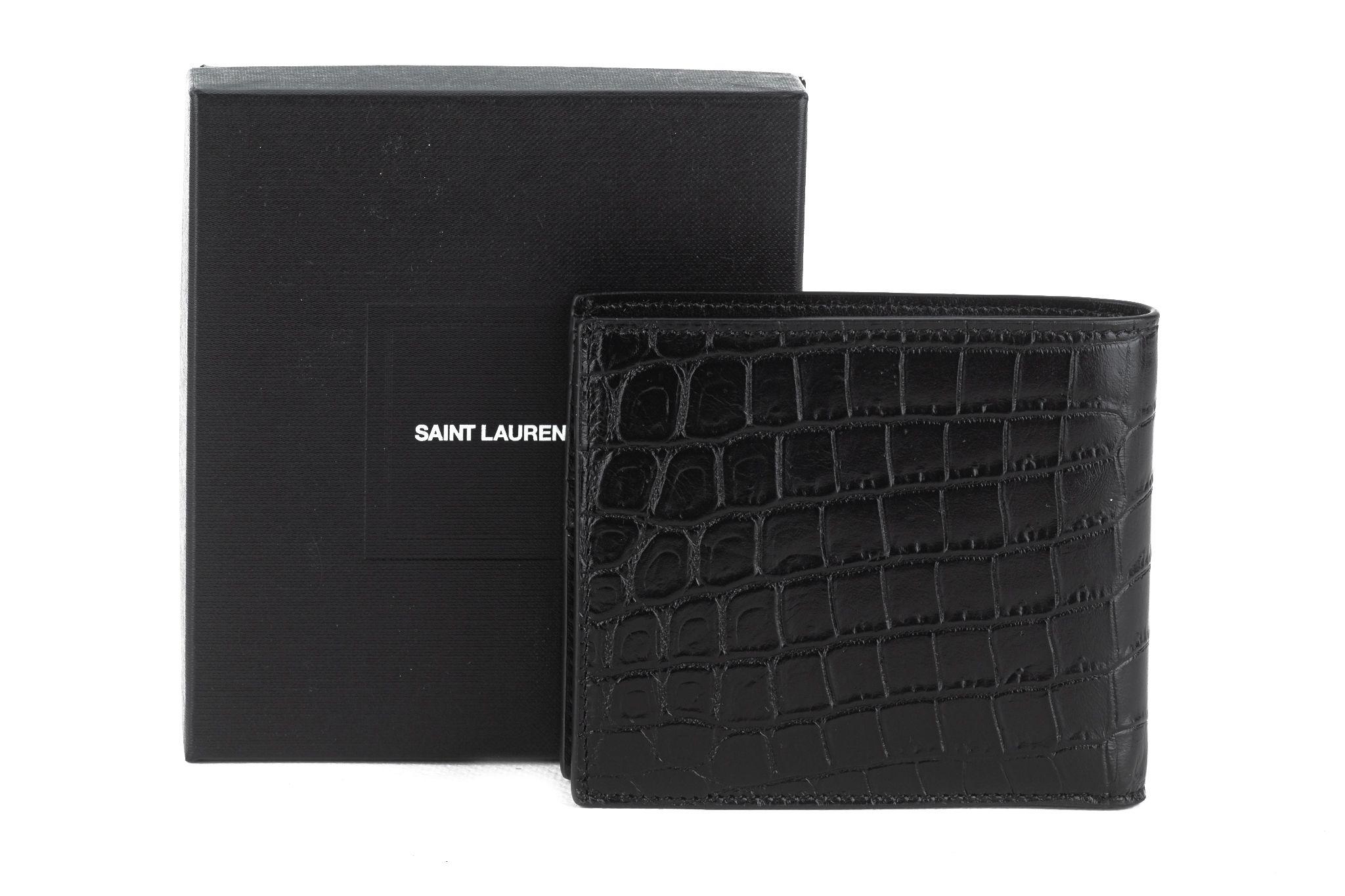 Cartera Saint Laurent Este-Oeste de piel de becerro grabada con cocodrilo en negro. Este tarjetero está confeccionado en piel de becerro repujada en negro. Esta cartera se abre en forma de carpeta a un interior compacto de piel negra con paneles de