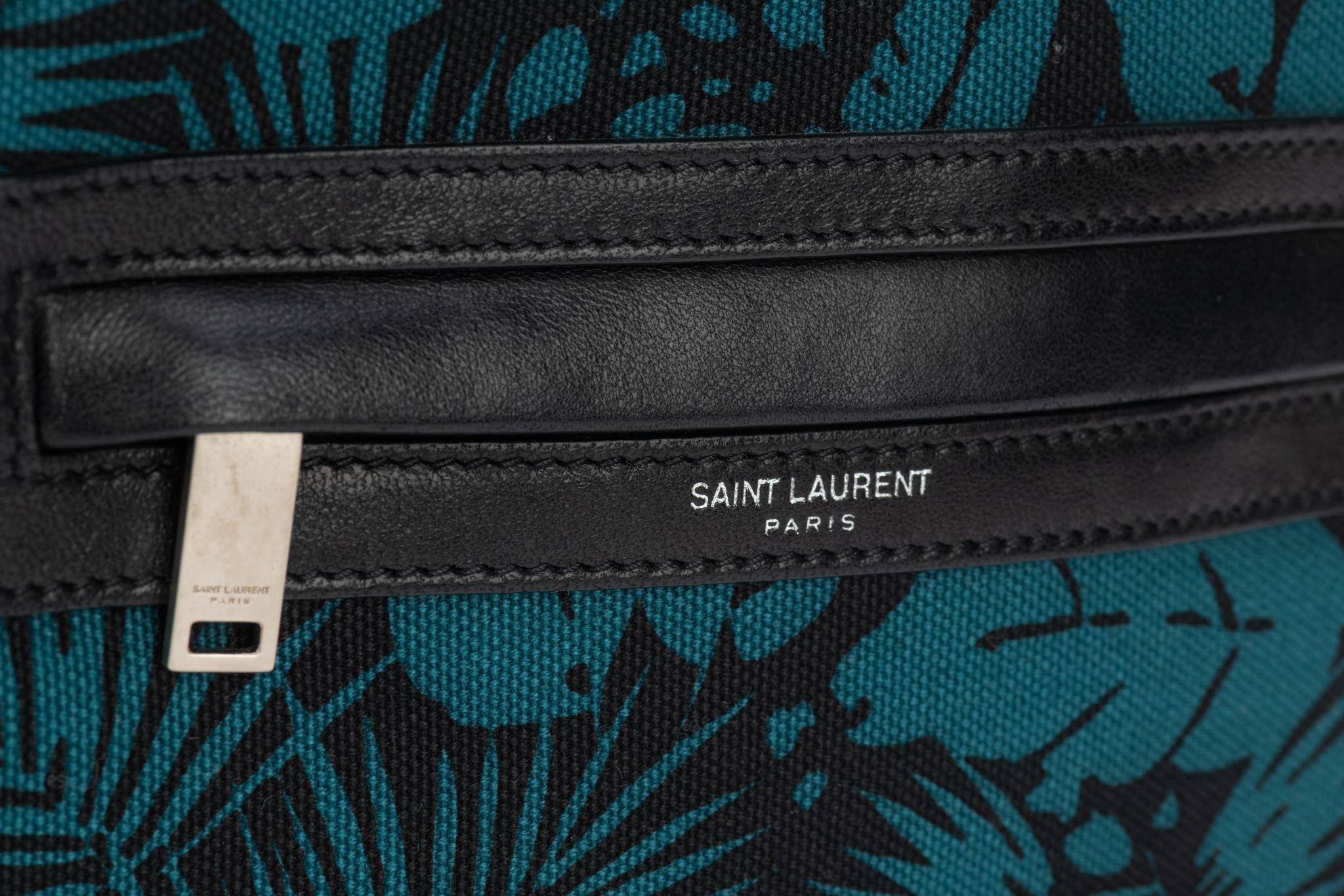 Saint Laurent canvas crossbody bag with palm print. The edges are trimmed with a Black Leather trim and comes with a strap. Shoulder drop 19”. The hardware is in silver. Its new and comes with booklet and dust bag.