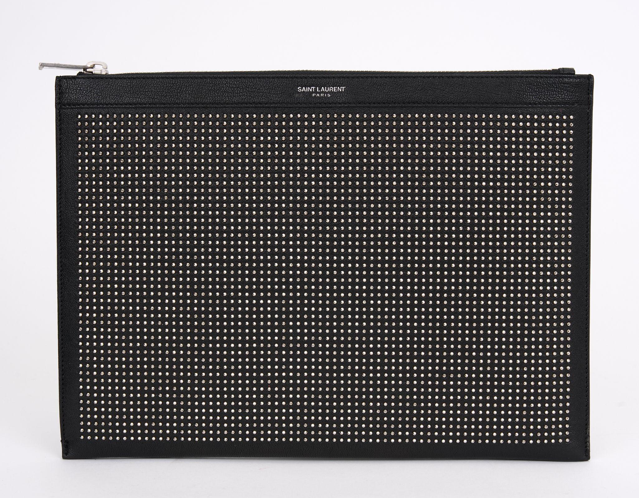 This Saint Laurent Portfolio features studded leather and silver tone hardware, 
twill lining  and single interior pocket with card slots, zip closure at top.
Comes with original box.